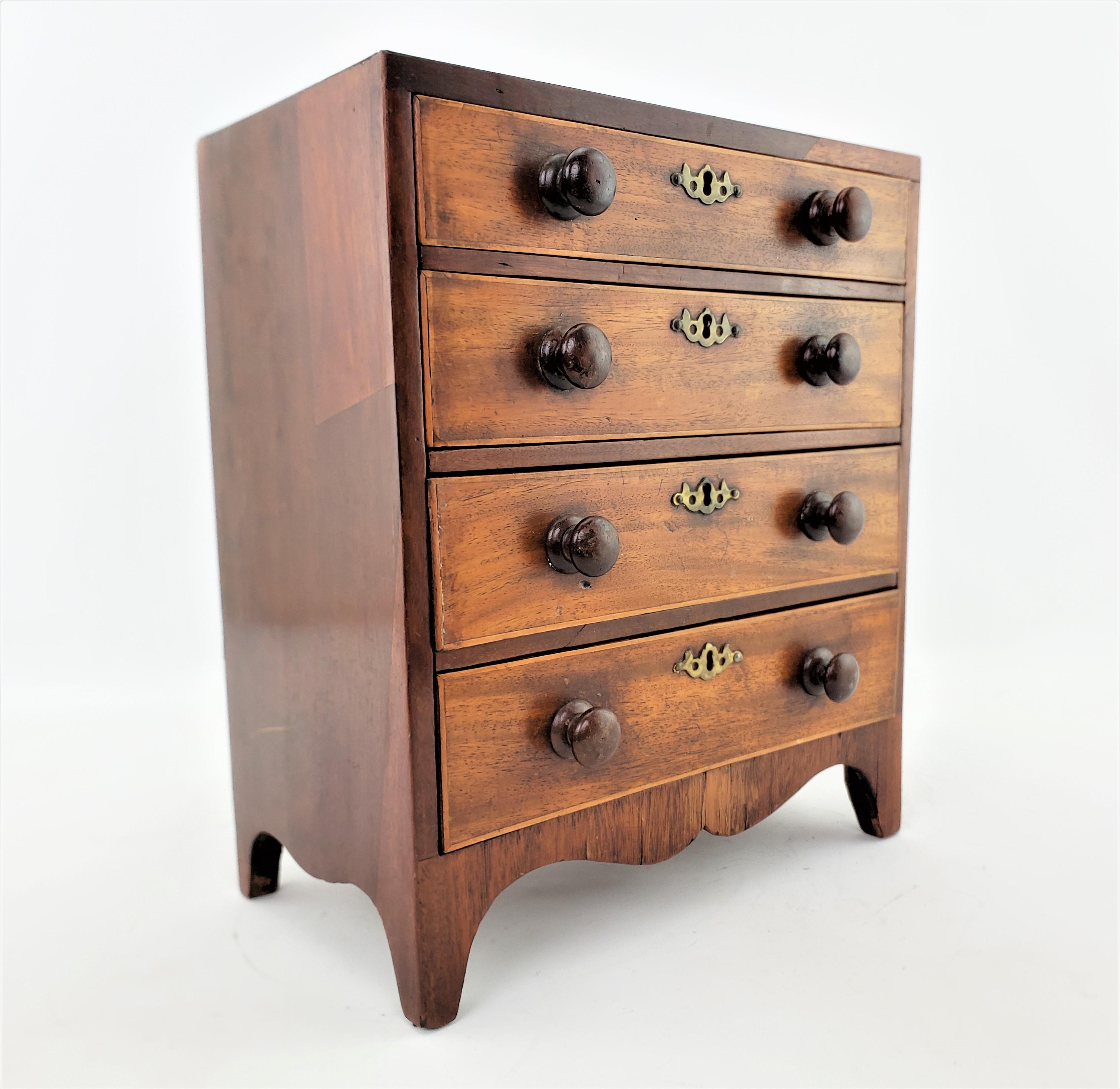 This minature table top sized chest of drawers is unsigned, but presumed to have originated from the United States and date to approximately 1880 and done in a Colonial style. This nicely exectued four drawer miniature tall boy is done with solid