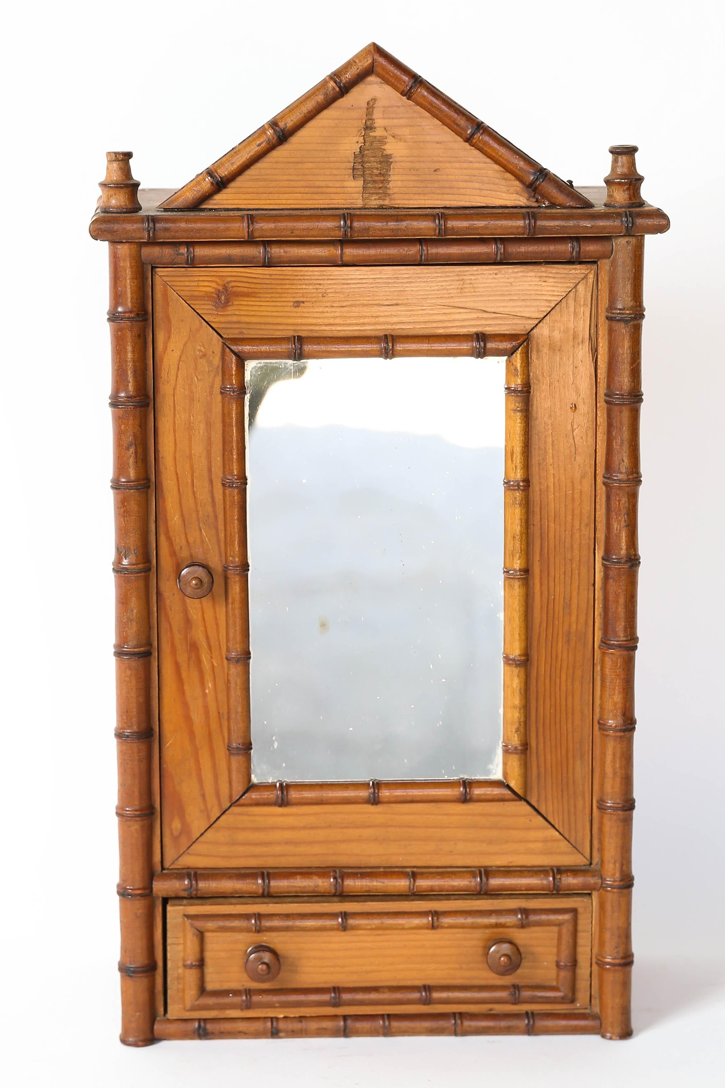 Antique French miniature armoire or wardrobe made from faux bamboo with a mirrored door and one drawer. The mirrored door opens leaving a wonderful space to attach hooks to hold necklaces. Below the door is a bottom drawer for other treasures. This