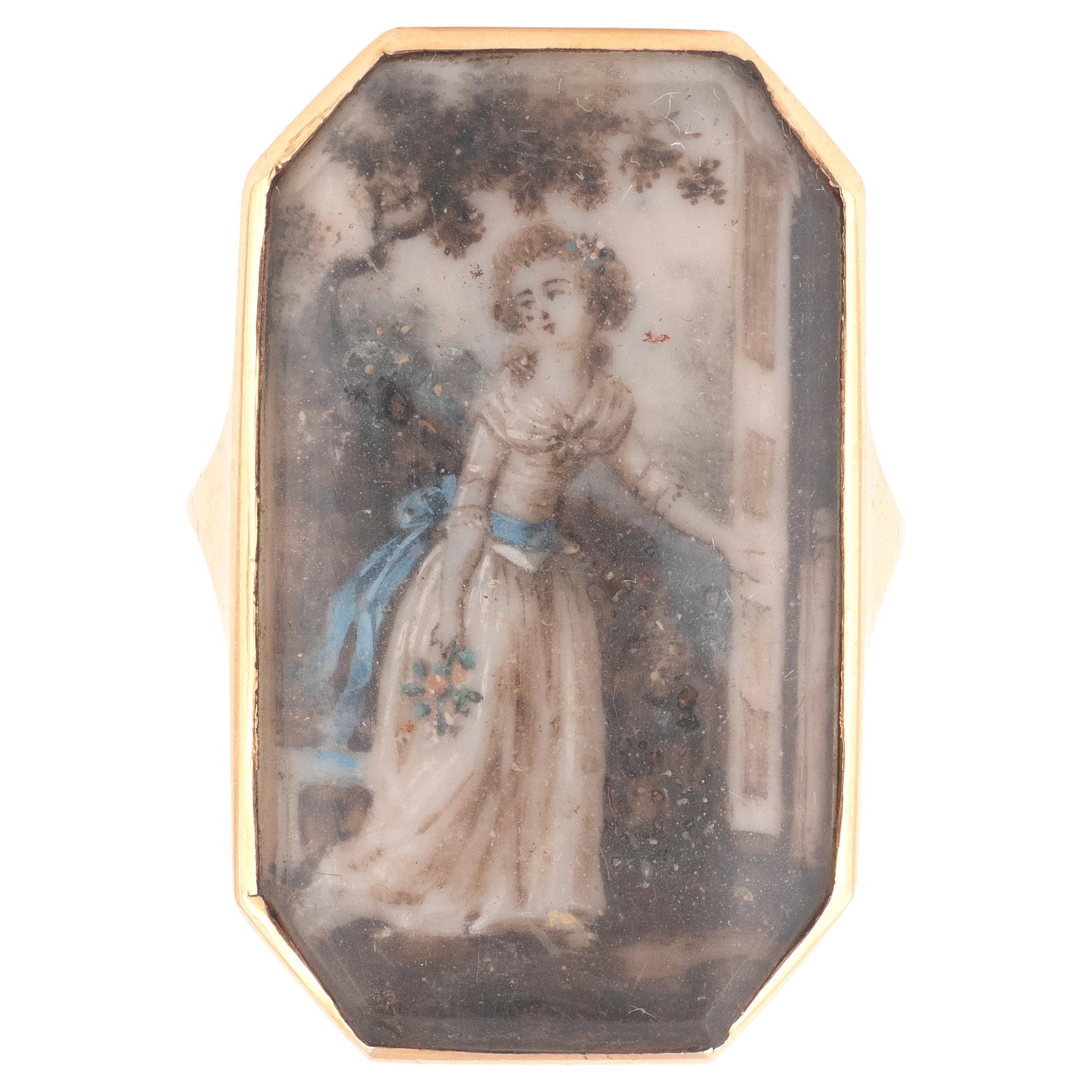 Miniature portrait octagonal ring in yellow gold 18 karats. Ring with a miniature depicting an elegant lady from the Revolutionary period protected by a glass. The ring’s band is plain and splits into gold strands at the shoulders to hold the ring’s