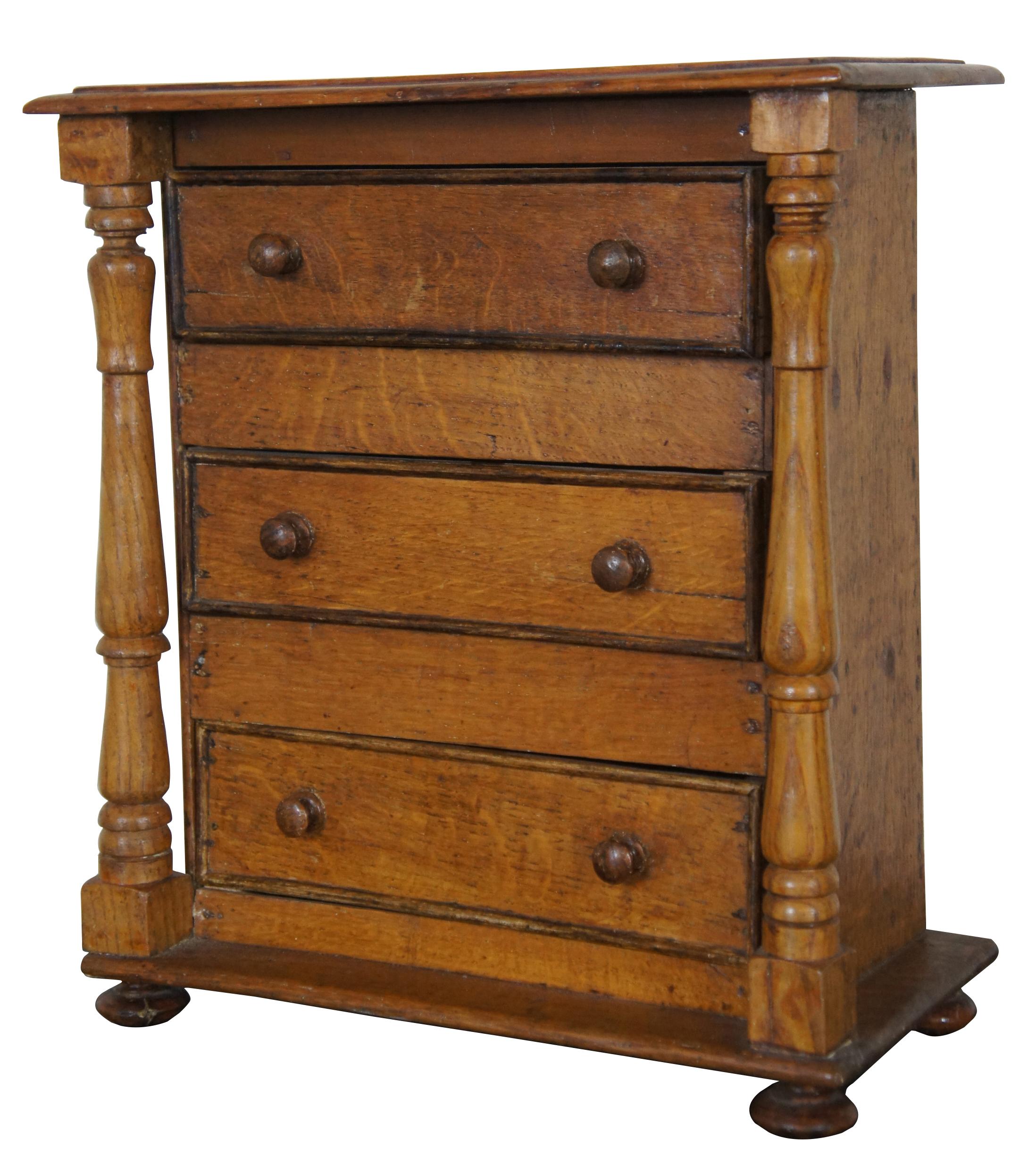 American Empire miniature salesman sample tallboy chest of drawers, circa 1850s. Made from quartersawn oak and pine with three drawers, turned posts and bun feet.
 