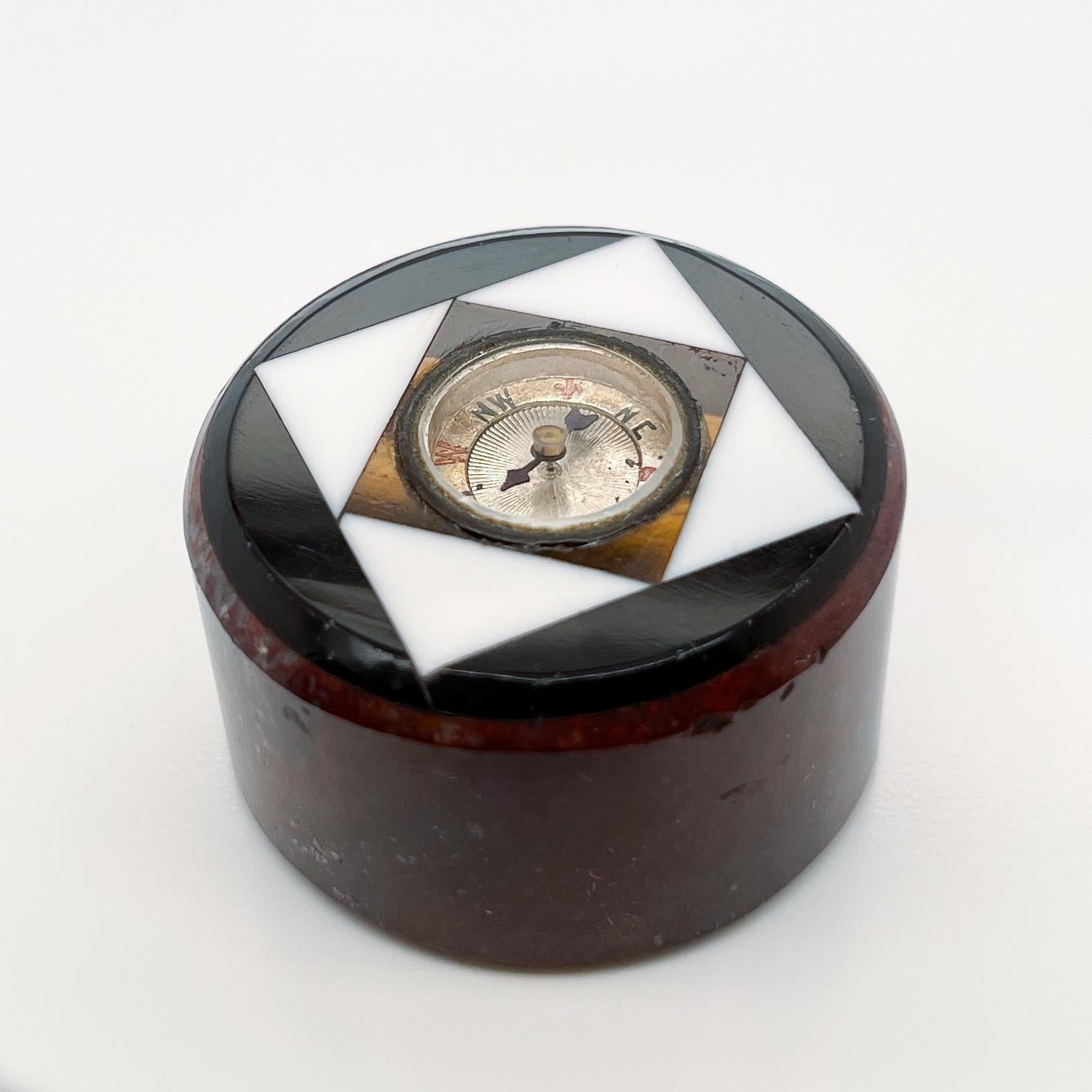 Eine feine Miniatur antiken Kompass.

Eingefasst in eine Matrix aus Edelsteinen und Hartsteinen.

Zu den Steinen gehören Tigerauge, weißer und schwarzer Onyx und ein roter Jaspis oder Marmorsockel.

Einfach ein wunderbares Stück Wunderkammer oder