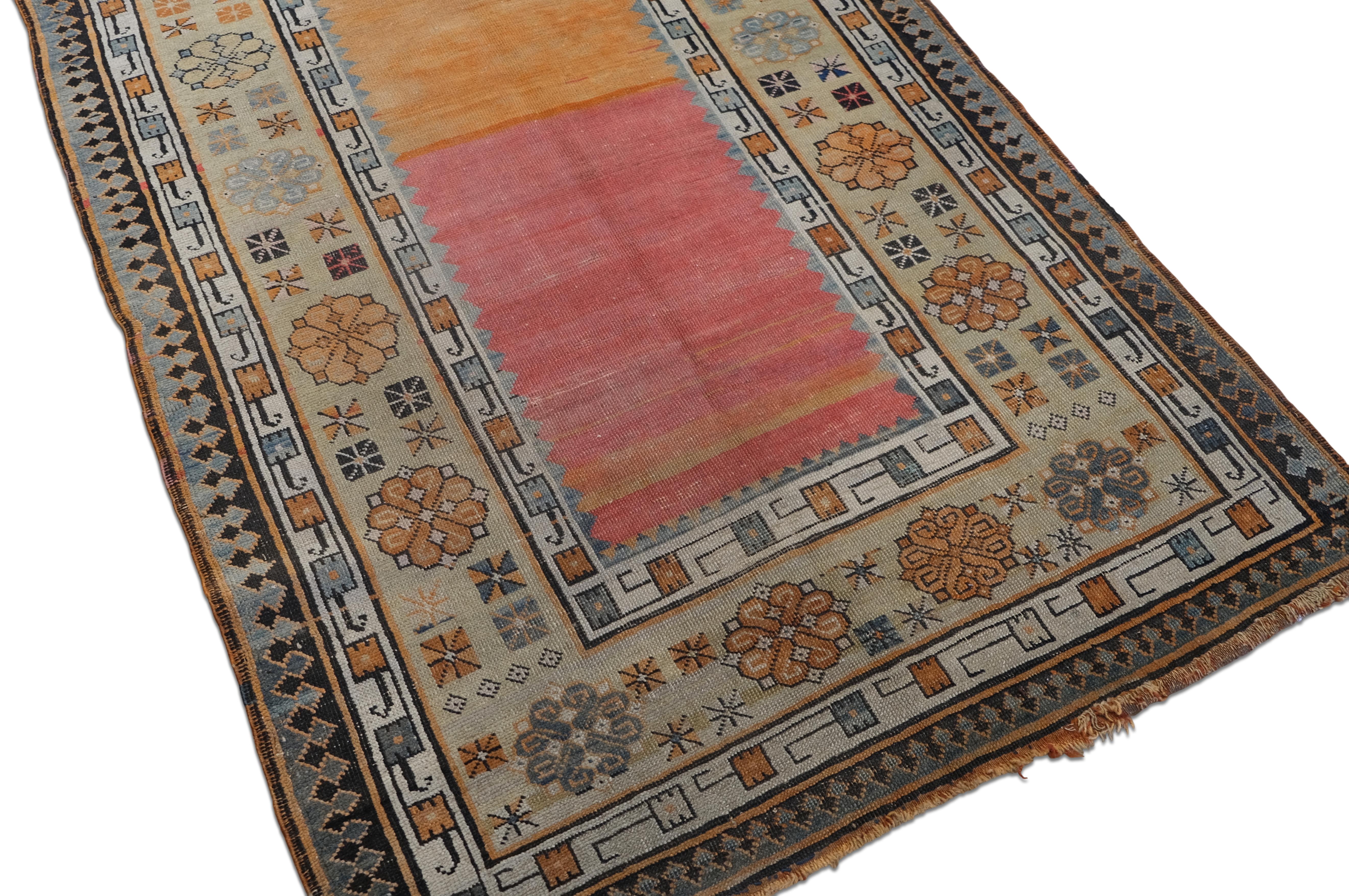 This antique hand-knotted wool runner, specifically the Karabagh tradition, showcases a rare and sophisticated balance of minimalism and intricate detailing. The rug’s open field design in pink, orange, ivory, deep blue hues creates a striking