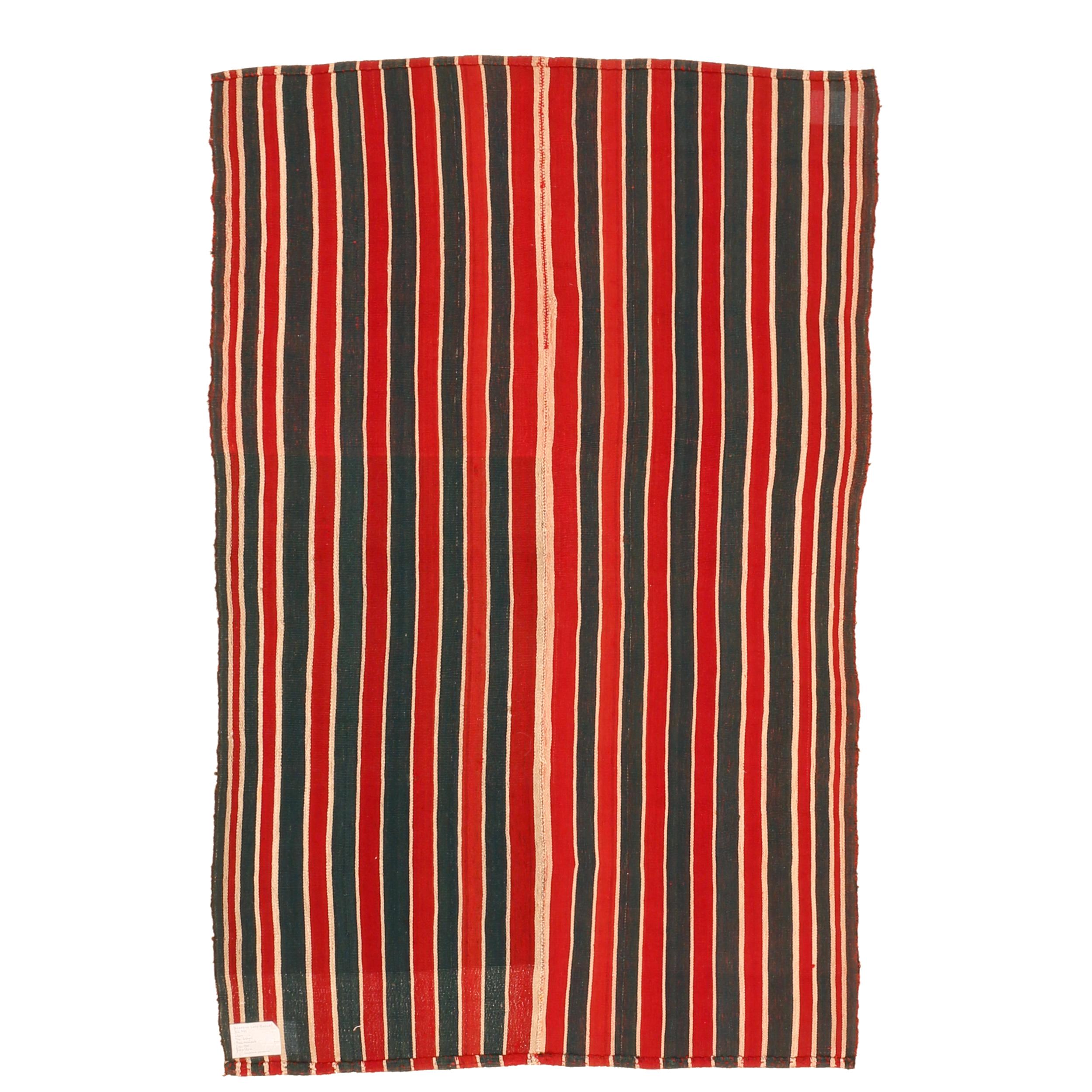 A very graphic tribal Kilim composed of two joined panels each containing a sequence of green and red vertical stripes of various widths, each framed by a narrow ivory stripe. The result is a wool flat-weave with a mirror image pattern having a