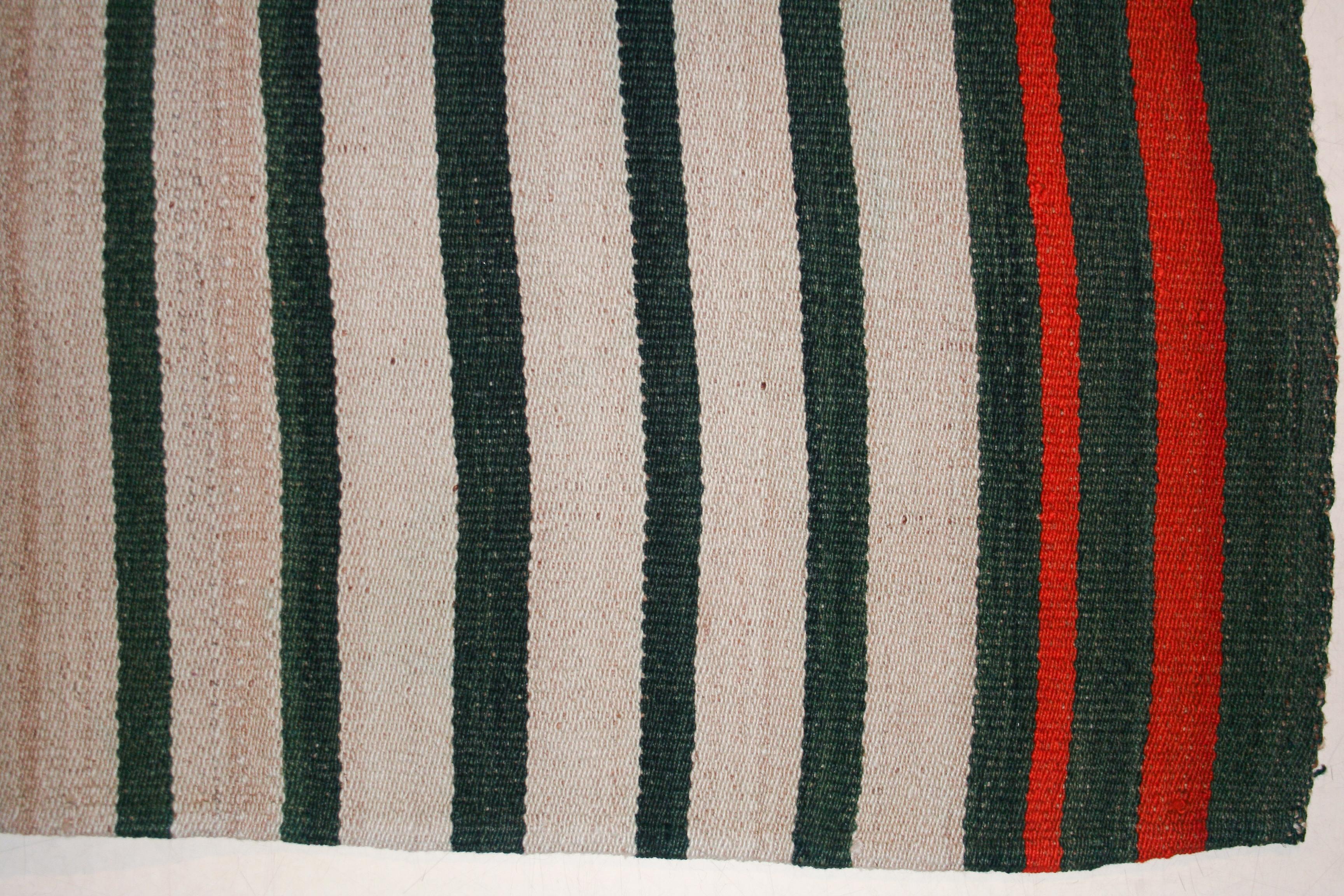 A very graphic tribal jajim wool flat-weave composed of two joined panels each containing an array of forest green stripes of varying widths on an ivory background. The result is a wool flat-weave with a mirror image pattern having a central stripe