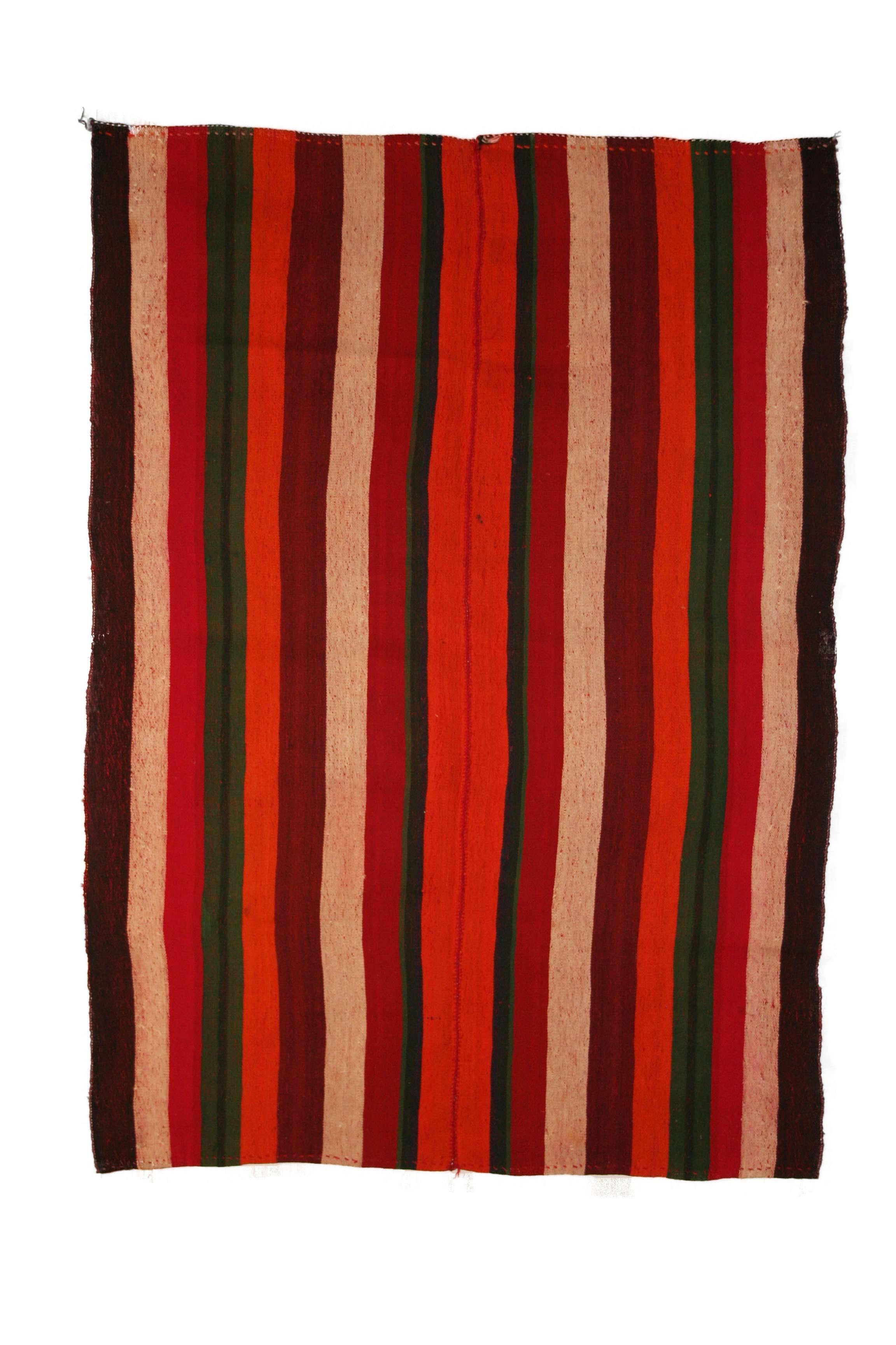 Un Kilim tribale molto grafico composto da due pannelli uniti che contengono ciascuno una serie di strisce verticali policrome di varia larghezza. Il risultato è una lana a trama piatta con un motivo a immagine speculare con una striscia centrale