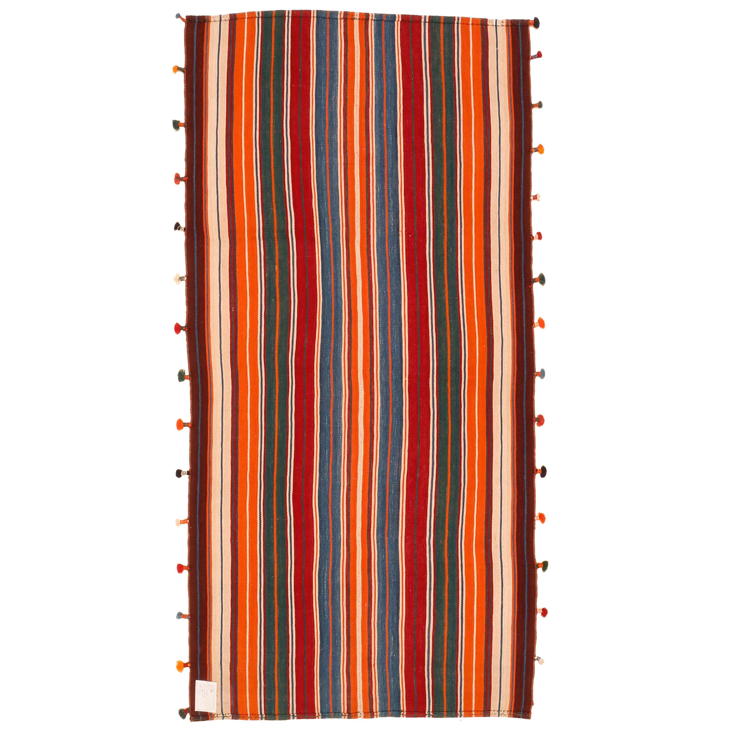 A graphic tribal kilim composed of two joined panels each containing an array of polychrome vertical stripes in a variety of natural colours. The result is a wool flat-weave with a mirror image pattern. What makes this example rather unique is the