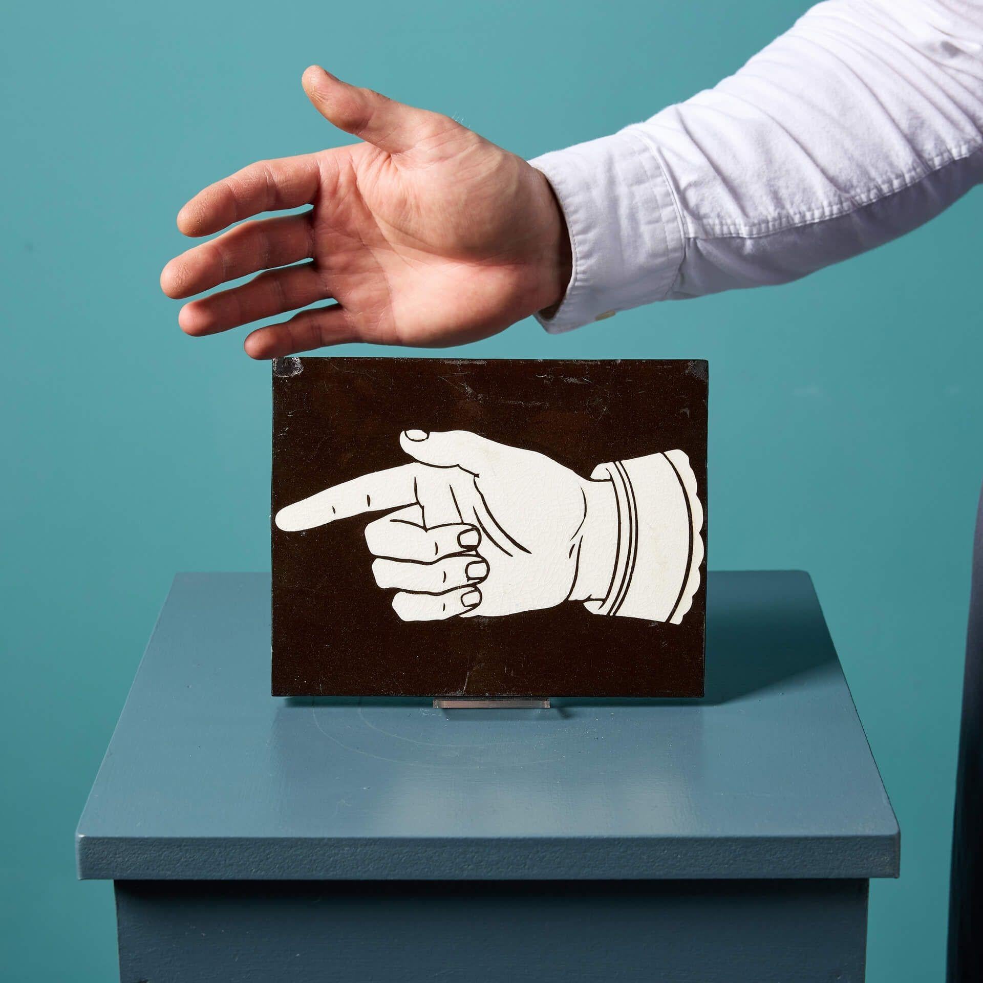 An antique Minton & Co encaustic tile of a left hand pointing.

This charming tile is decorated with a Victorian style white pointing finger over a sleek black finish.

Dating to circa 1880, this tile would make a unique decorative piece in modern