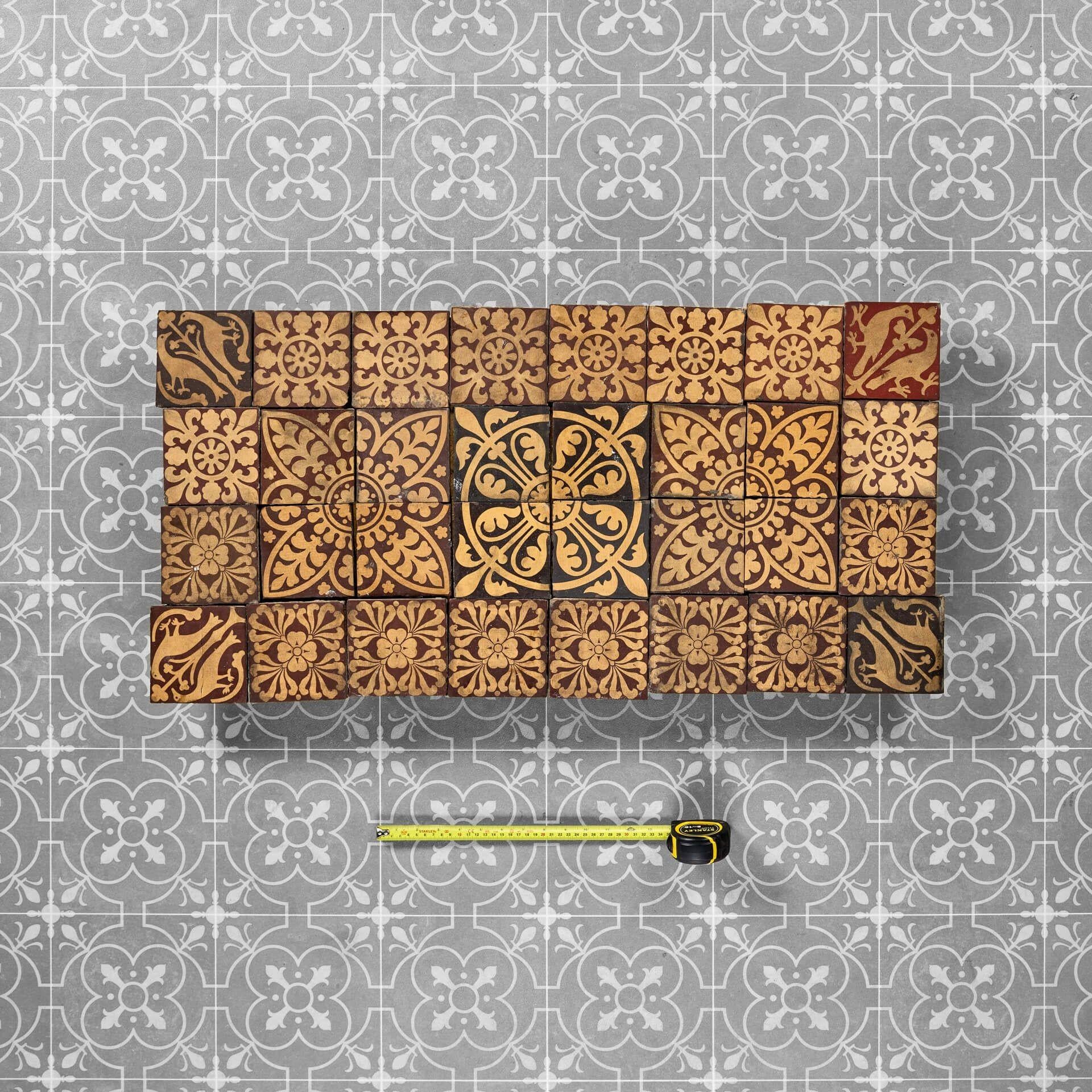 Un ensemble de 32 carreaux de Minton récupérés, idéal pour un dosseret de carreaux anciens, un sol d'entrée ou un foyer de cheminée dans un cottage d'époque ou une propriété de l'ère victorienne.

L'ensemble comprend divers motifs de carreaux