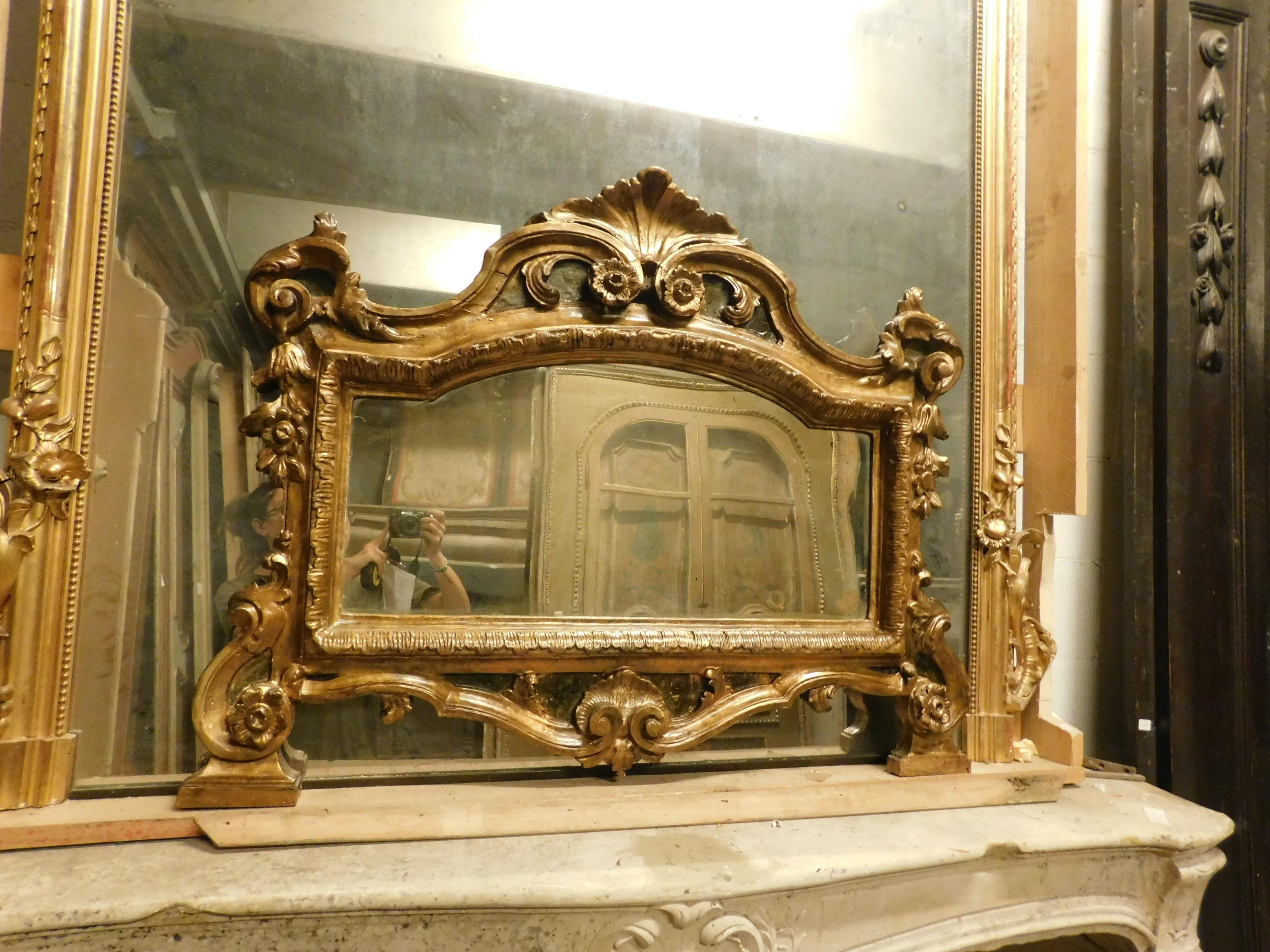 Miroir ancien sculpté à la main, richement garni de fioritures en bois doré et laqué, construit au XIXe siècle en Italie,
avec coquille centrale et disposée horizontalement, mesurant cm L 108 x H 85, parfaite pour une cheminée ou un meuble de