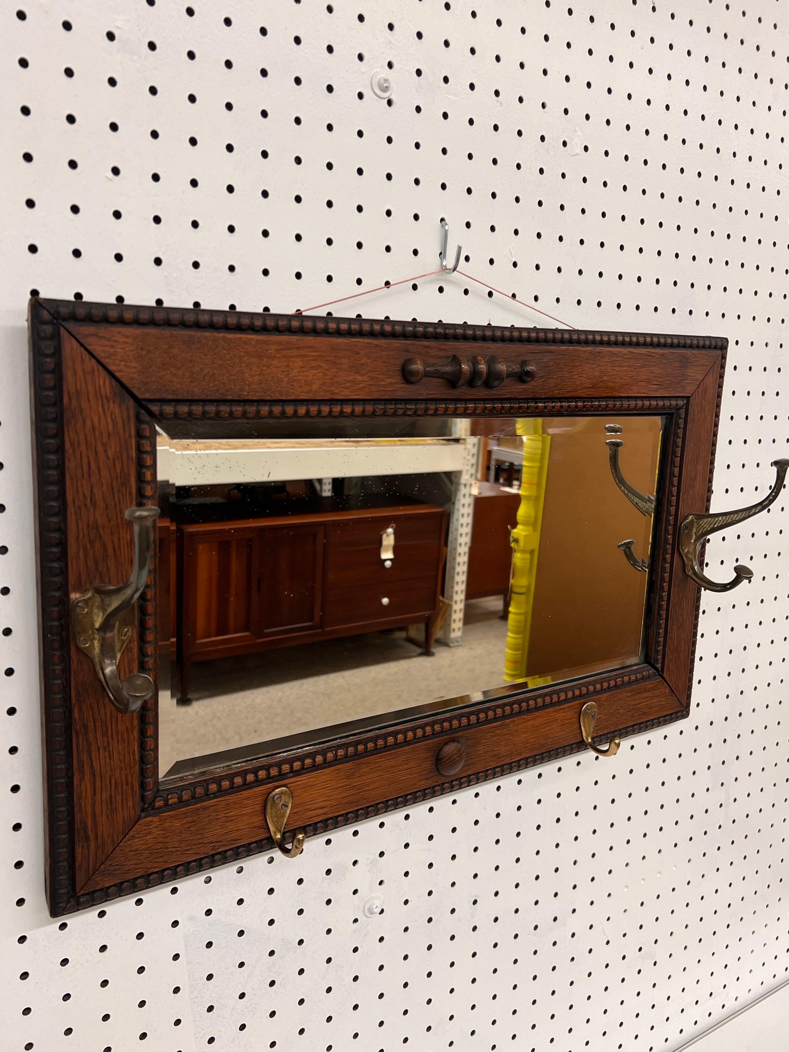Espejo de pared antiguo enmarcado en una rica madera de roble oscuro aserrada en cuarto con detalles decorativos en los bordes. El marco presenta un dibujo texturizado y un borde ligeramente elevado, lo que le da un aspecto clásico. El aspecto