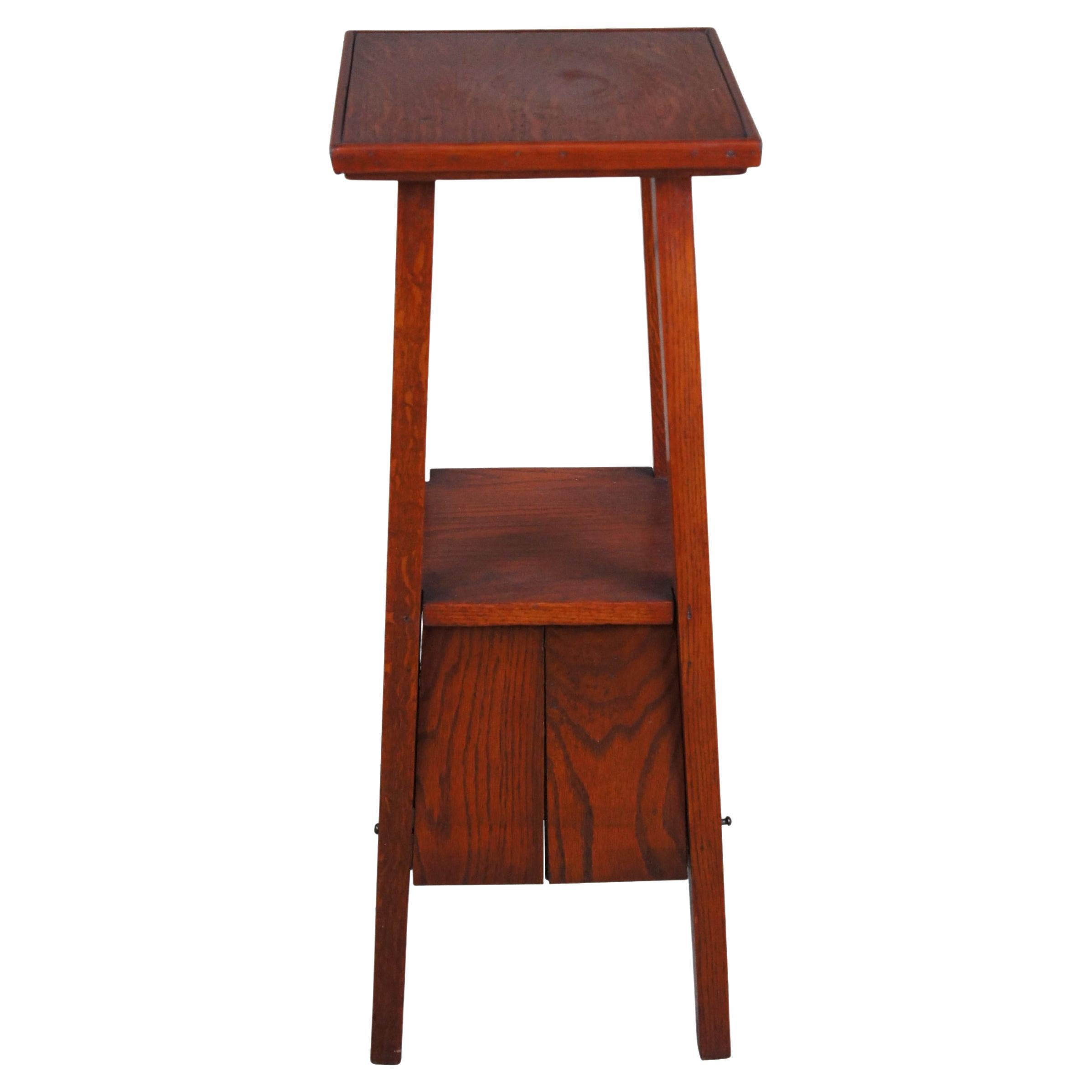 An early 1900s craftsman tiered smoking stand with lower concealed drop front cabinet. Made from oak with long square posts.