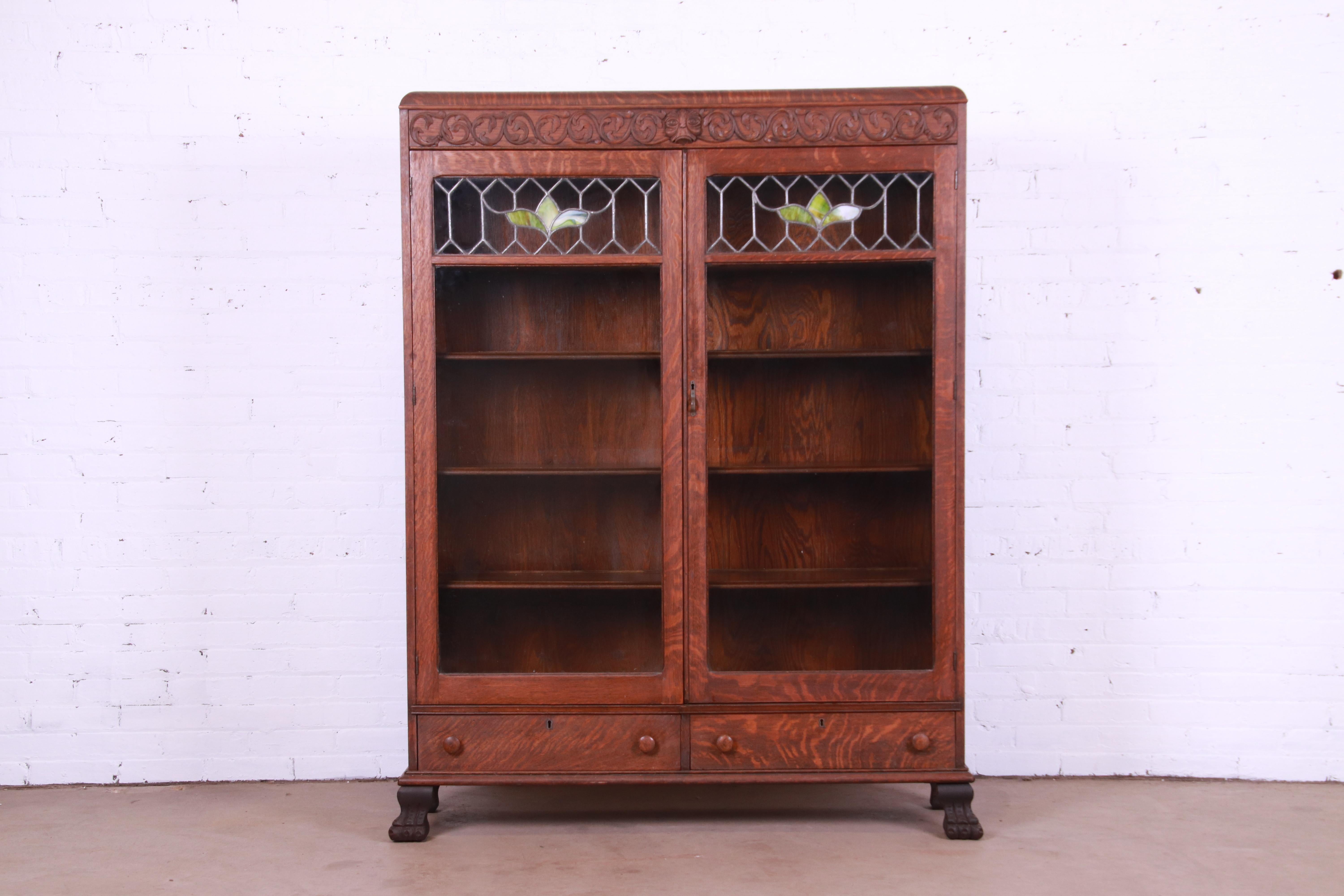 A gorgeous antique late Victorian or Arts & Crafts bookcase cabinet

By Sheboygan Novelty Co.

USA, Circa 1900

Carved quarter sawn oak, with stained leaded glass doors and paw feet.

Measures: 51