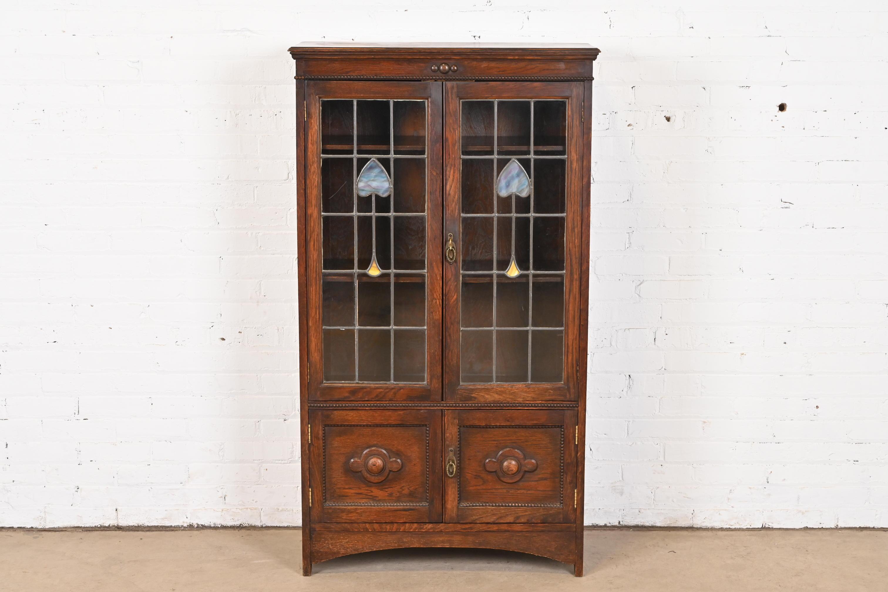 A gorgeous antique Late Victorian or Arts & Crafts bookcase cabinet

USA, Circa 1900

Carved oak, with stained leaded glass doors.

Measures: 31.5