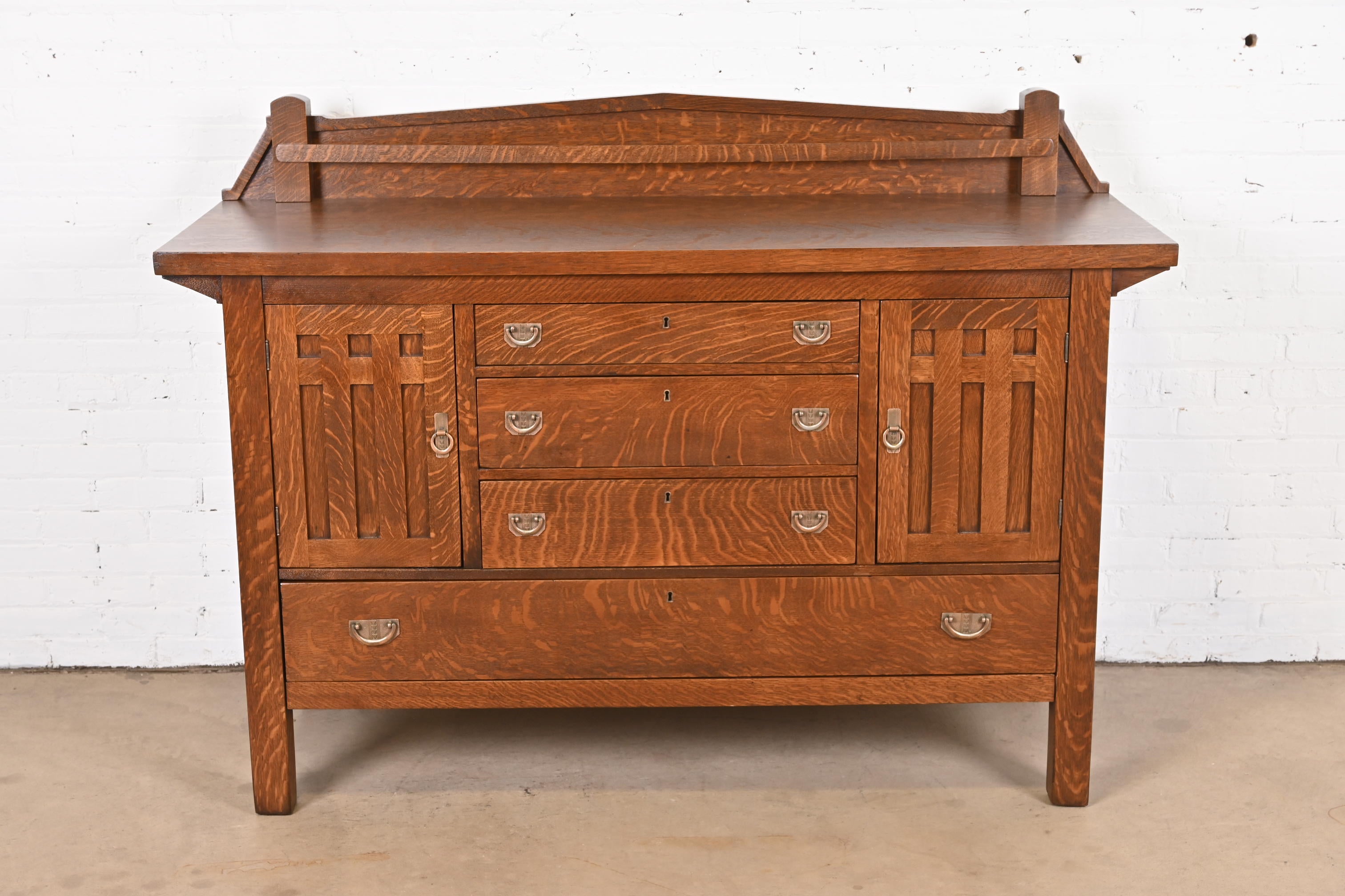 A beautiful antique Mission oak Arts & Crafts sideboard, credenza, or bar cabinet

In the manner of Stickley Brothers

USA, Circa 1900

Quarter sawn oak, with original hammered copper hardware.

Measures: 64