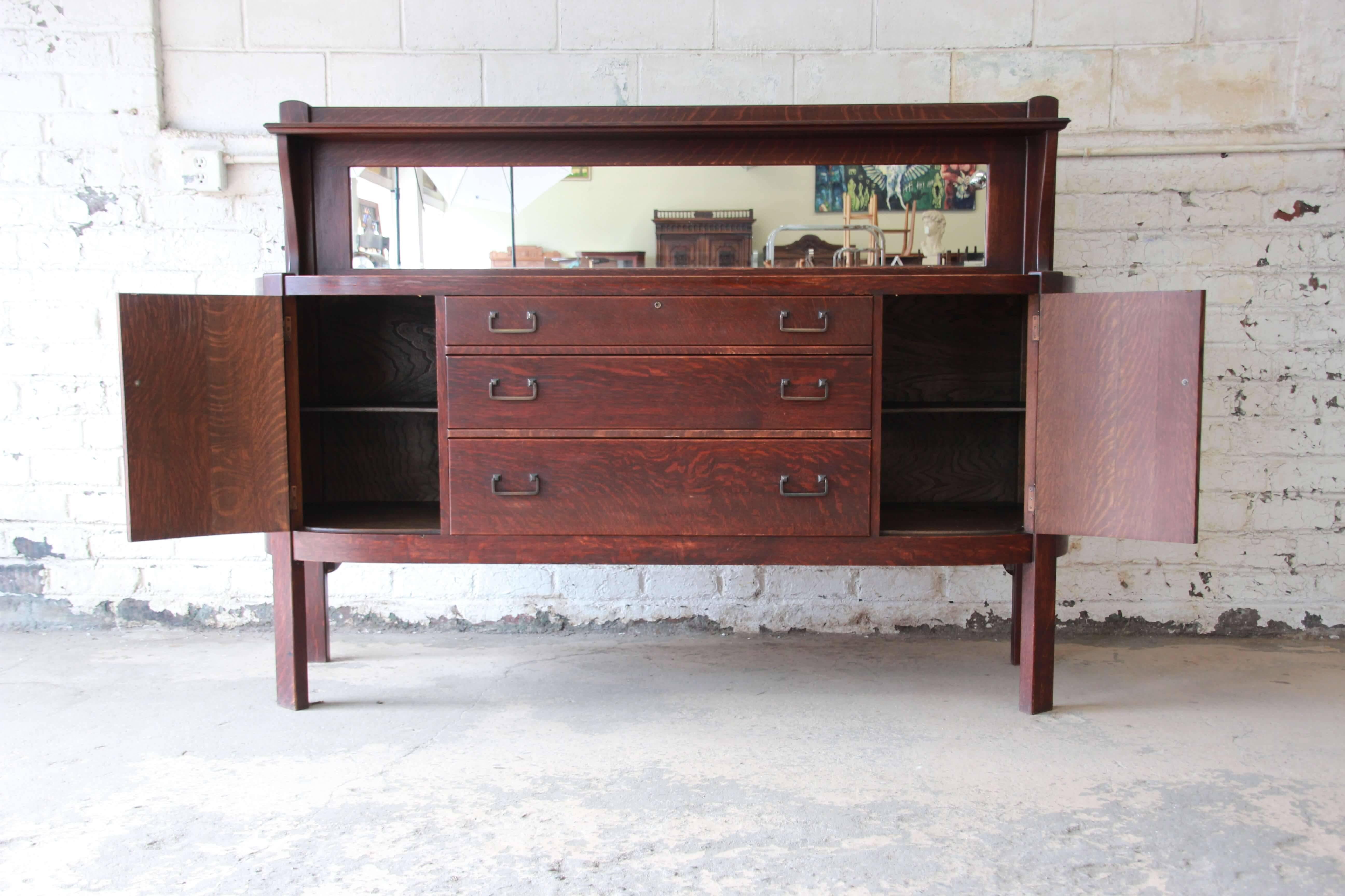 Offering a rare and stunning Mission quarter sawn oak sideboard credenza by Grand Rapids Chair Co. The sideboard feature round slated side cabinet that open up to a shelf for storage. The center has three additional drawers for storage. It has a