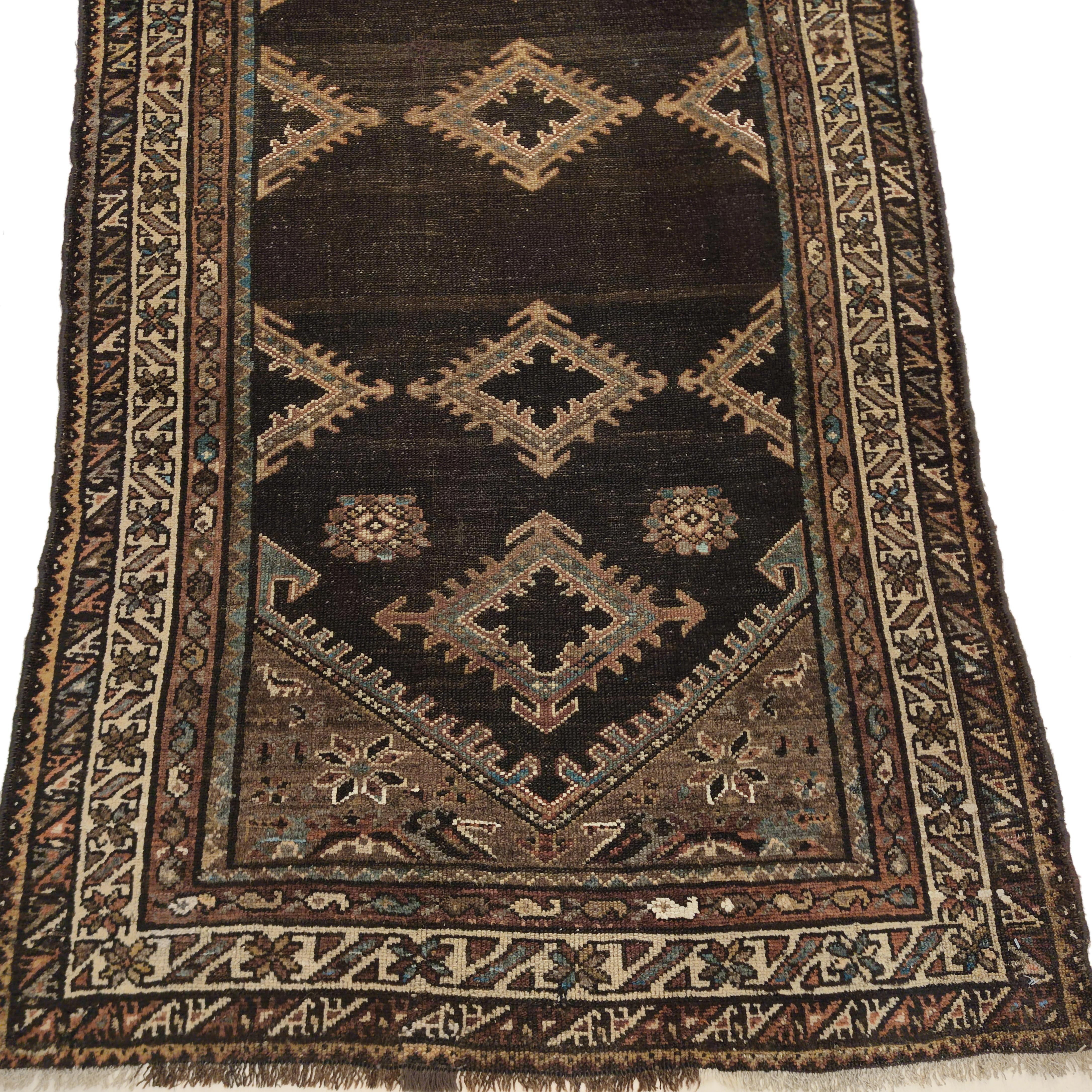 La inusual paleta bicolor de esta alfombra larga Bakshaish distingue a este ejemplo del grupo, ya que éstas suelen mostrar una coloración más tradicional. El fondo está escasamente adornado con hileras horizontales de pequeños diamantes en colores