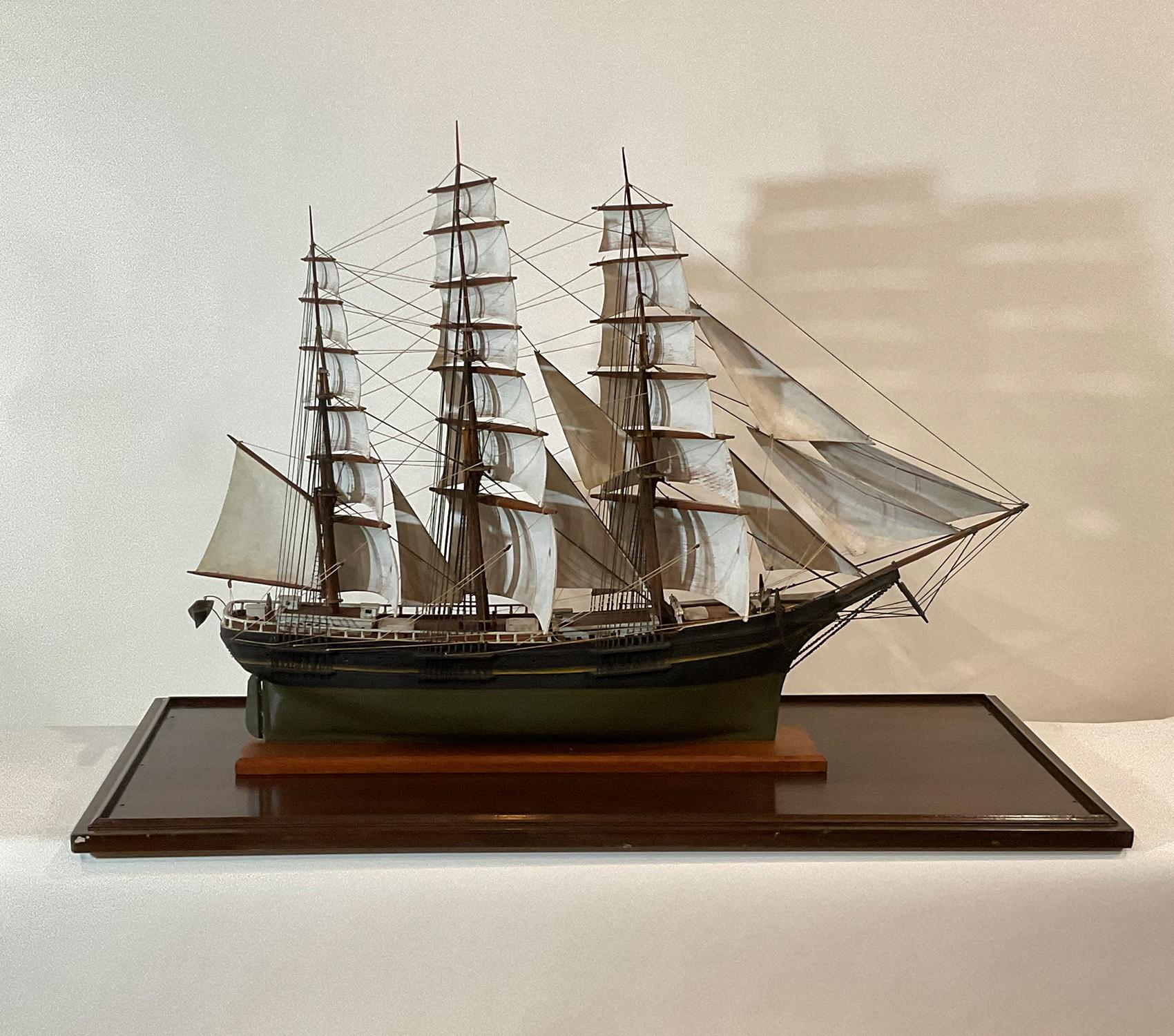 Carved wood sails set at a graceful angle on the three masts. Details include surrounding railing, cabins, hatches, capstan, anchors, chain, scribed deck, wheel, etc. Set into a case with old glass and museum inventory number.

Weight: 76