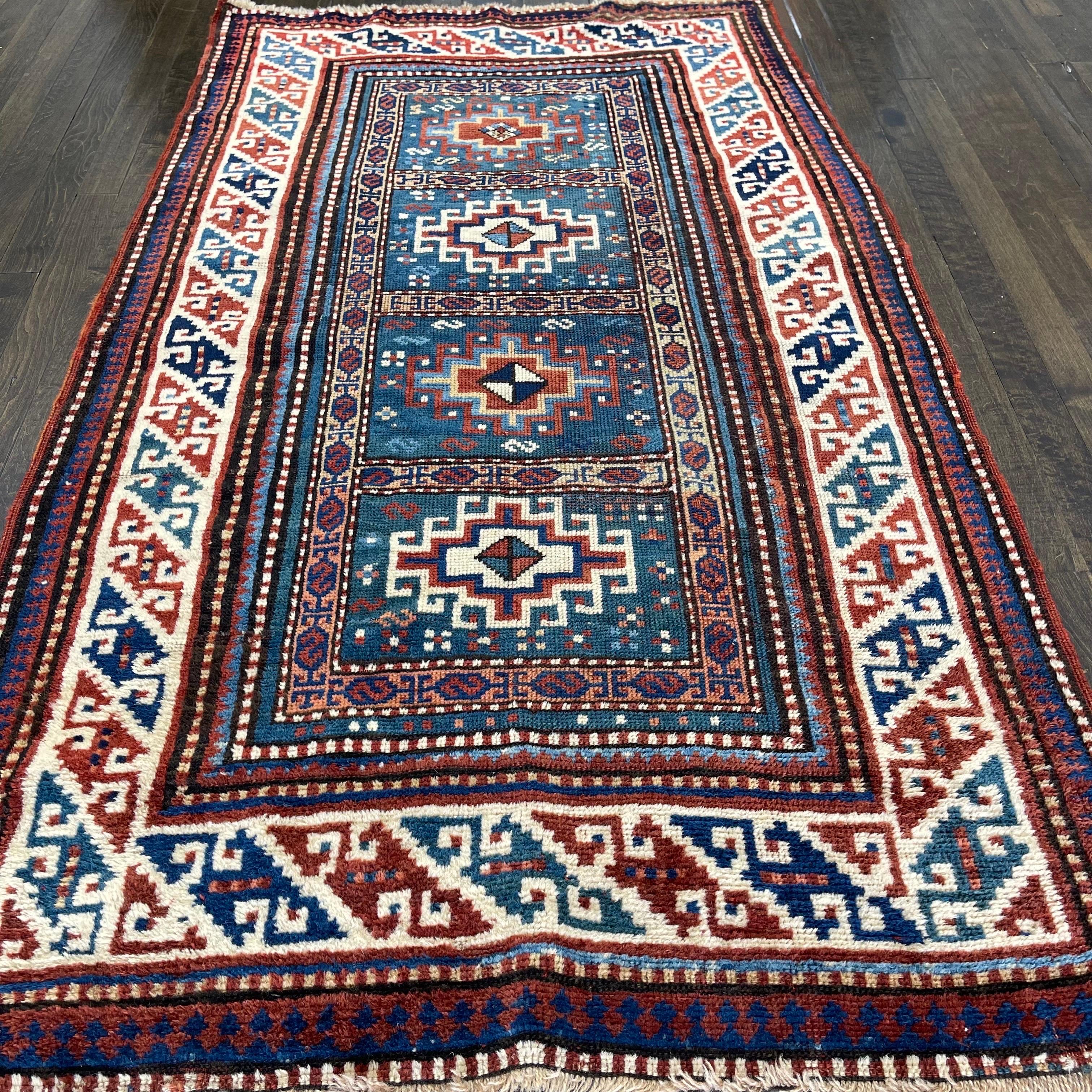 A beautiful example of Moghan kazak created by artisans of the caucus featuring four rows of Memlinc gul lattice on a turquoise field.Each of these Memlinc gul is woven within a square boxed with S border in tan color.This compartmental design is