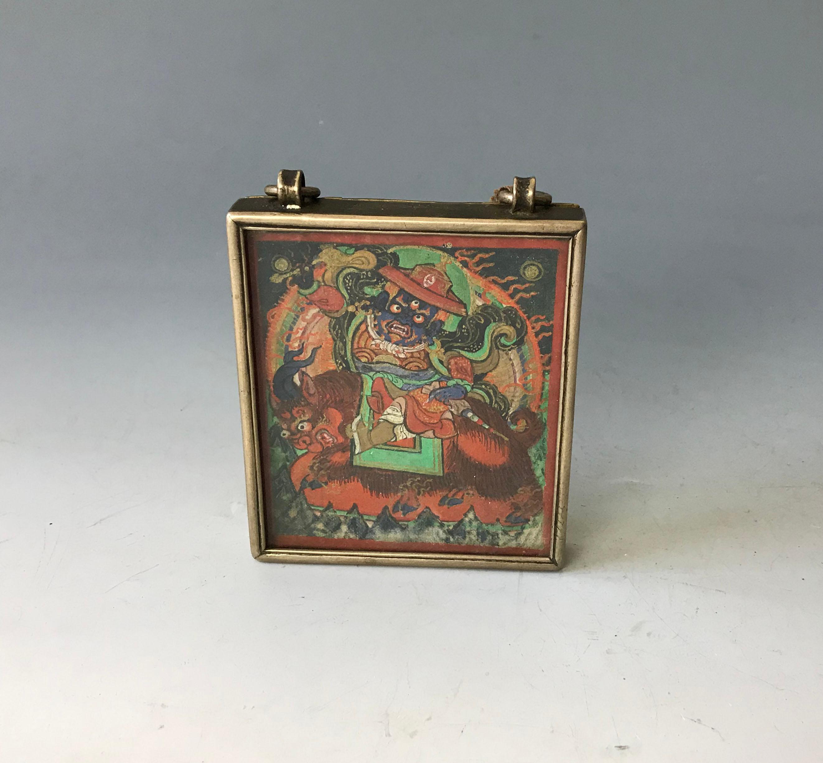 Antique Mongolian Gau box
Central painted deity under glass with silver alloy sides engraved with religious script, brass backing with central painting and interior images. The Ga`u Buddhist religious artifact and is used as a small traveling shrine