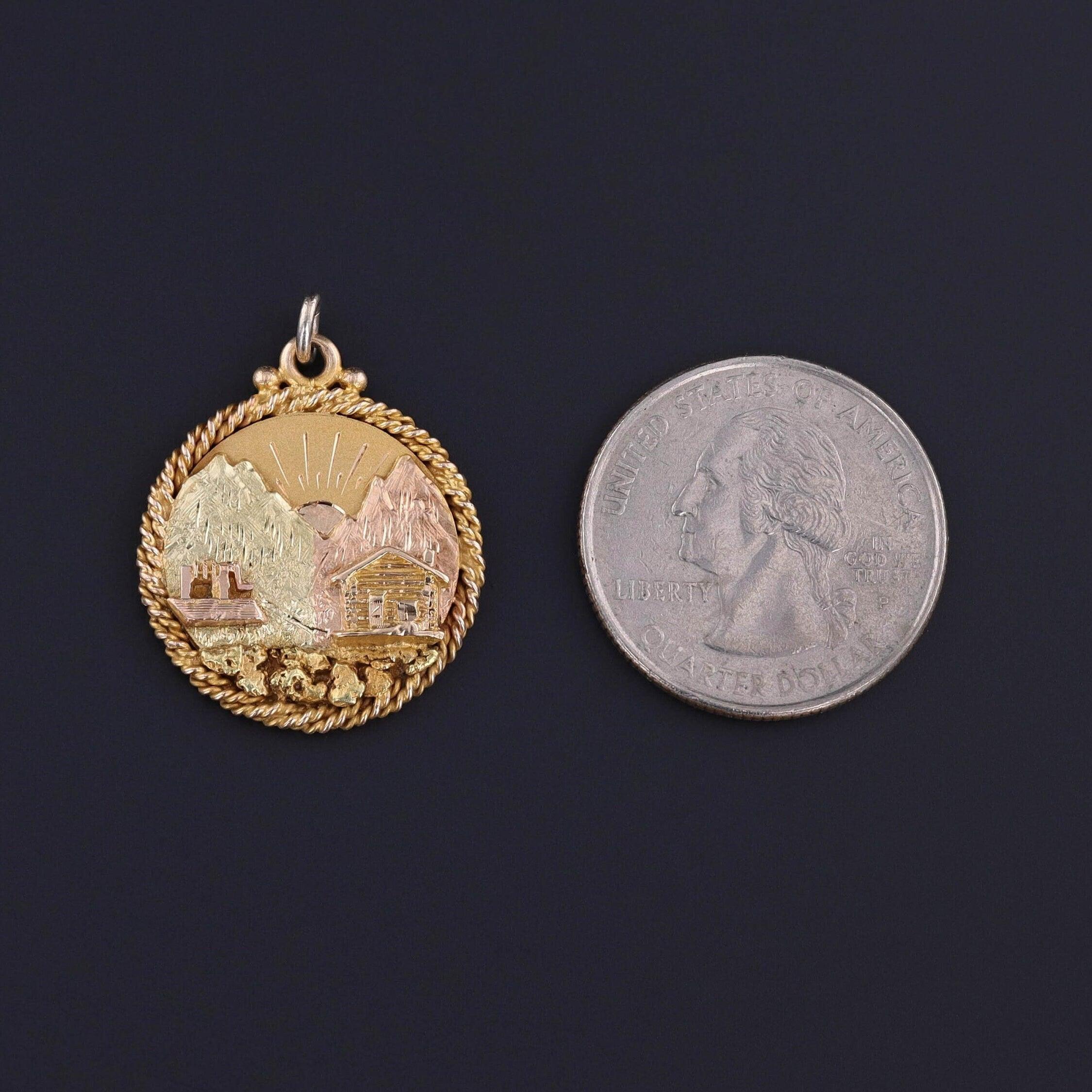 Transport yourself to a bygone era with this enchanting antique pendant, dating to the early 1900s. The pendant showcases a picturesque landscape, where the sun rises over a cozy cabin nestled amidst majestic mountains. Crafted with a blend of gold