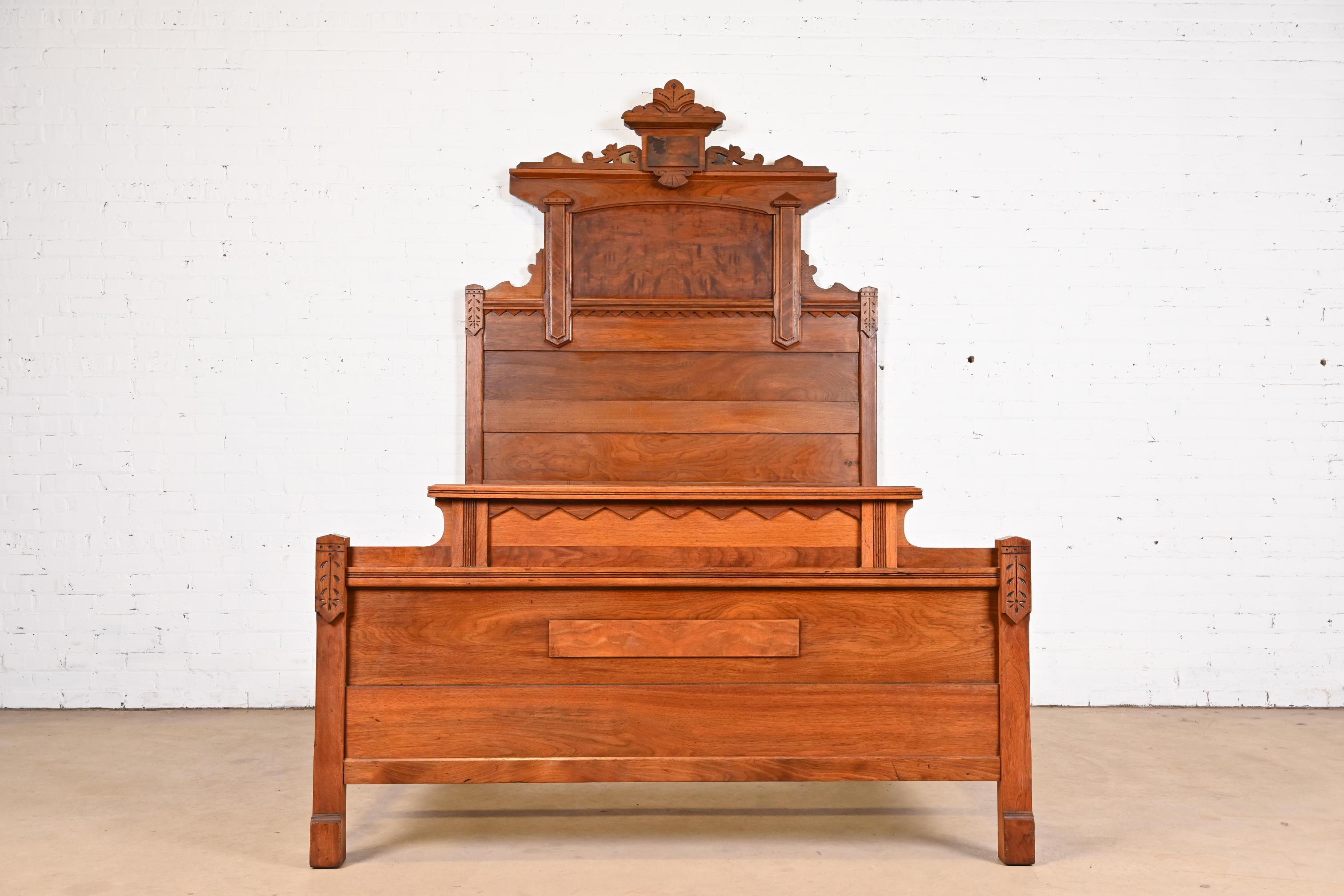 A gorgeous monumental antique Eastlake Victorian full size bed frame

In the manner of Herter Brothers

USA, Circa 1880s

Carved solid walnut, with burled walnut panels.

Measures: 57.25