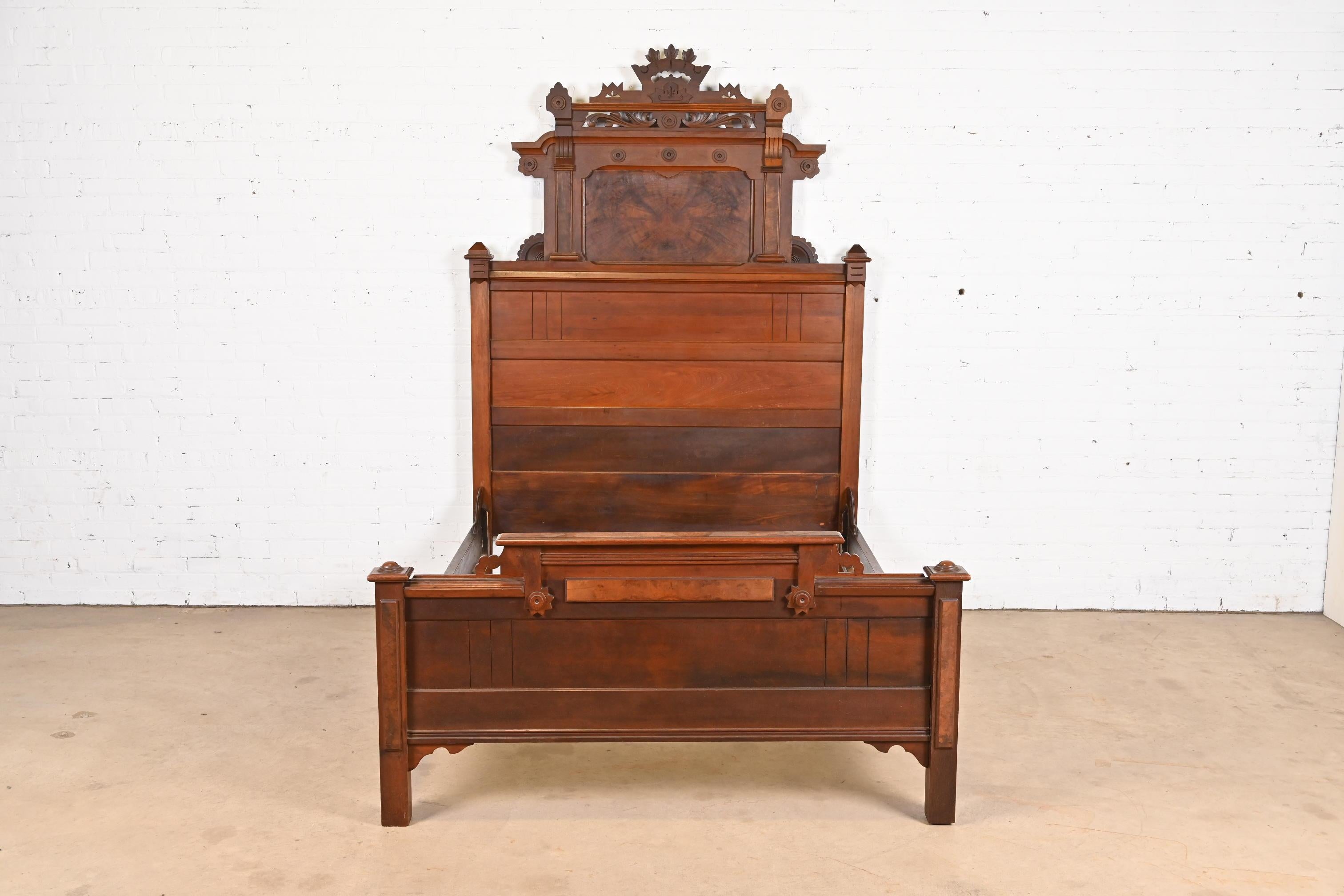 A gorgeous monumental antique Eastlake Victorian  full size bed frame

In the manner of Herter Brothers

USA, Circa 1880s

Carved walnut, with burled walnut panels.

Measures: 59