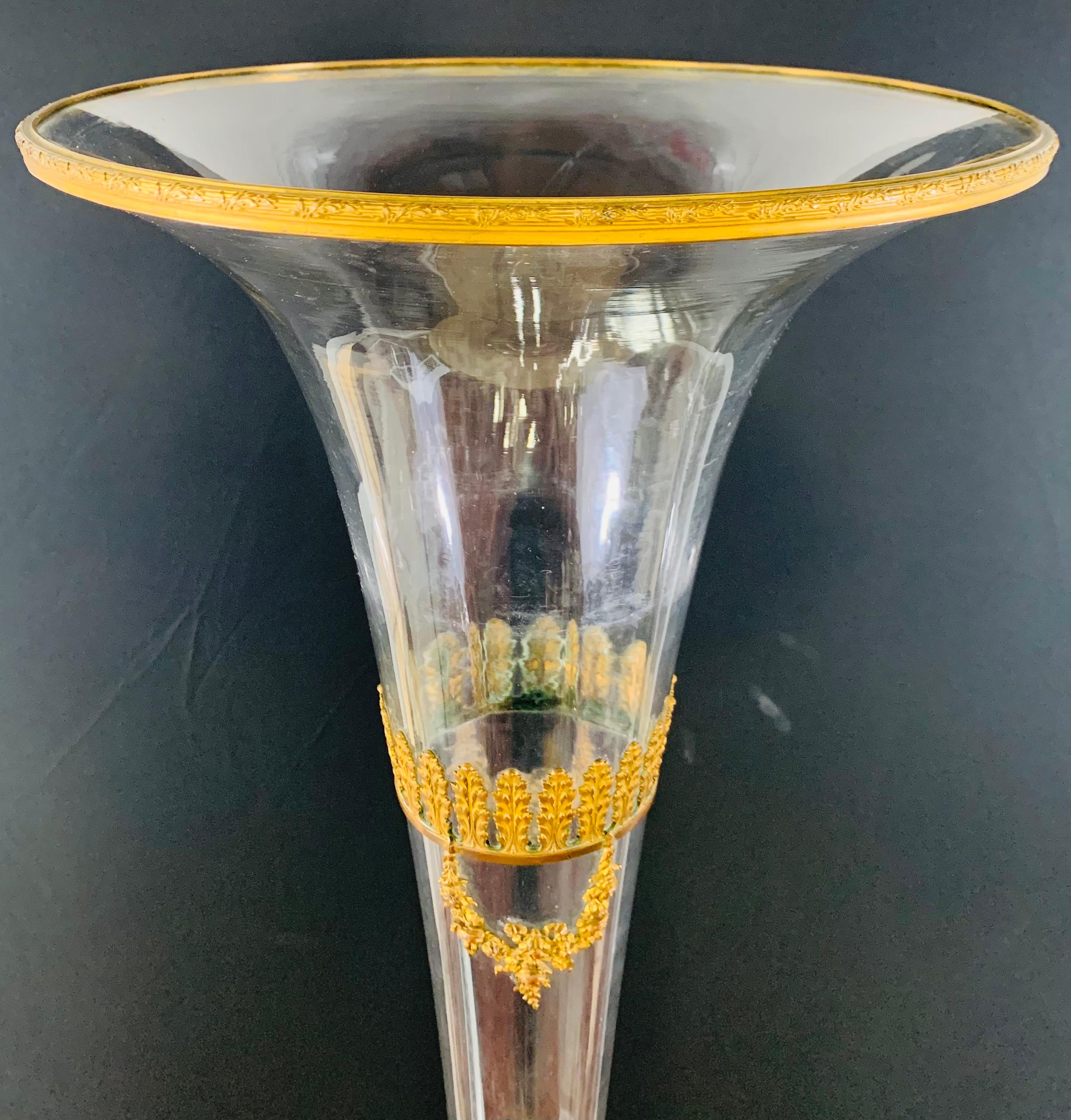 An early 20th century monumental floriform art glass long neck vase or flower vase. The vase featutres mounted decorative brass inlay. The rim of the vase shows fine tree branches design whole the neck and bottom are finely decorated in acanthus and