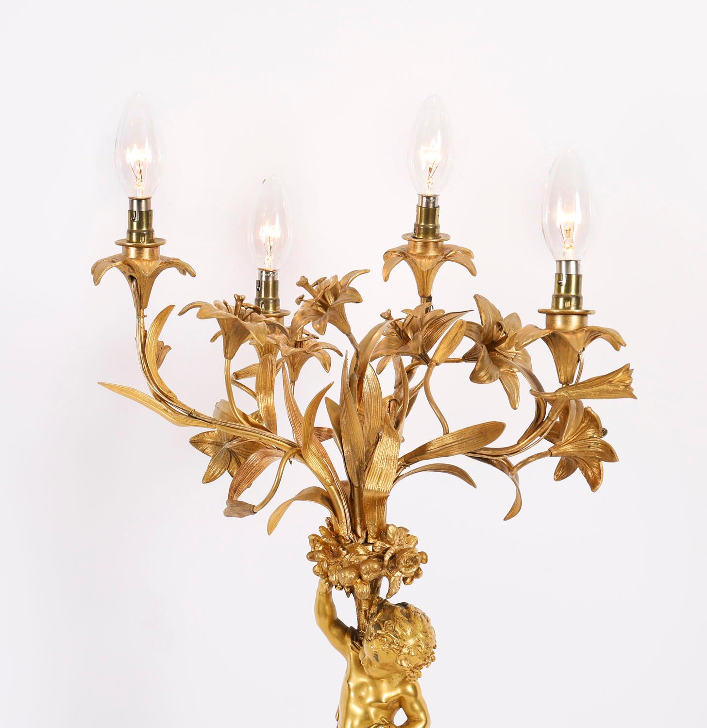 Il s'agit d'une lampe de table à quatre lumières en bronze doré de grande qualité, datant d'environ 1870.

Réalisée par le procédé de la cire perdue, elle présente une sculpture décorative en bronze doré d'un chérubin tenant un panier de récolte