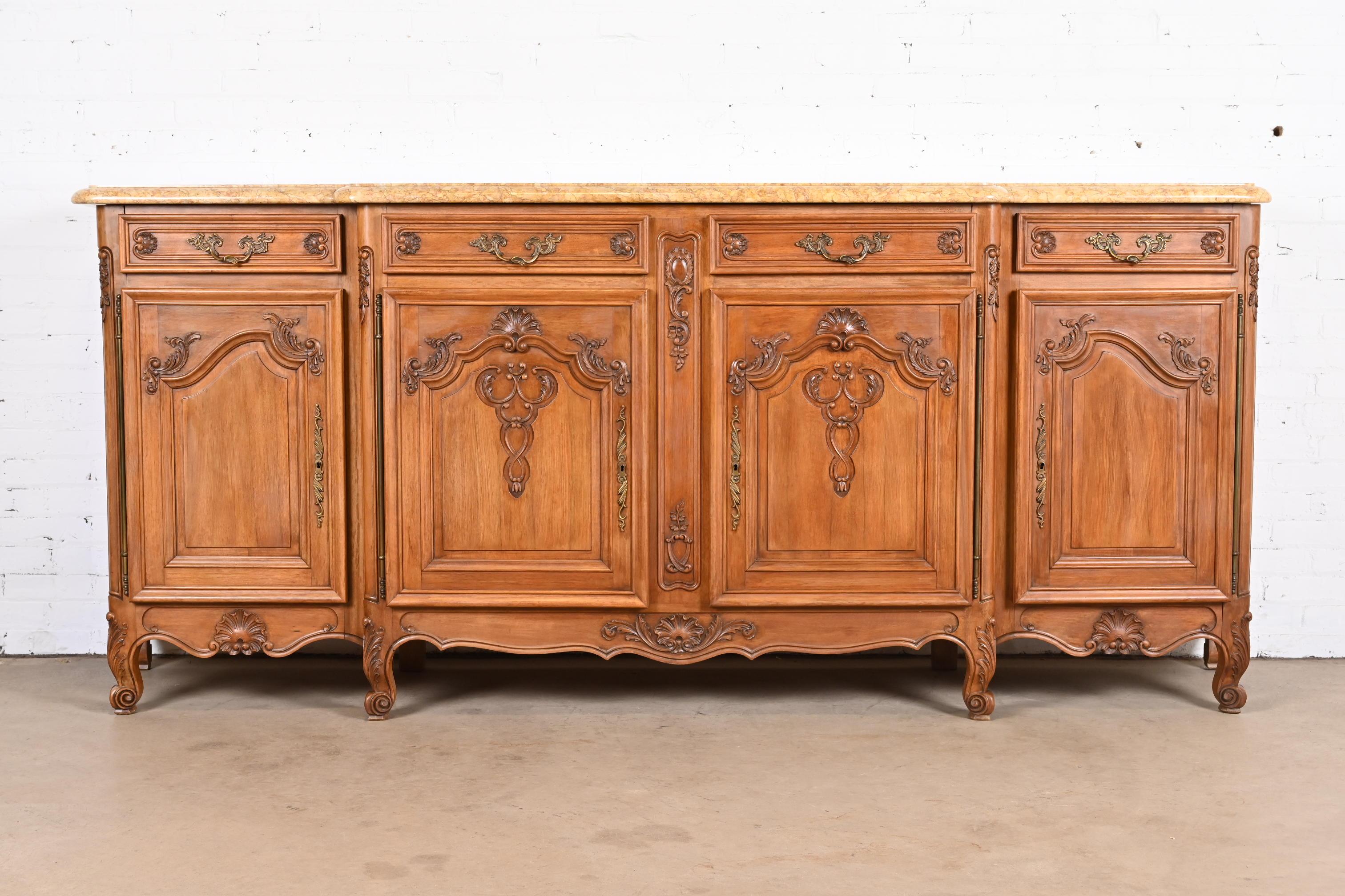 An outstanding French Provincial Louis XV style monumental sideboard, credenza, or bar cabinet

France, early 20th century

Carved walnut, with thick beveled marble top and original brass hardware.

Measures: 103.75