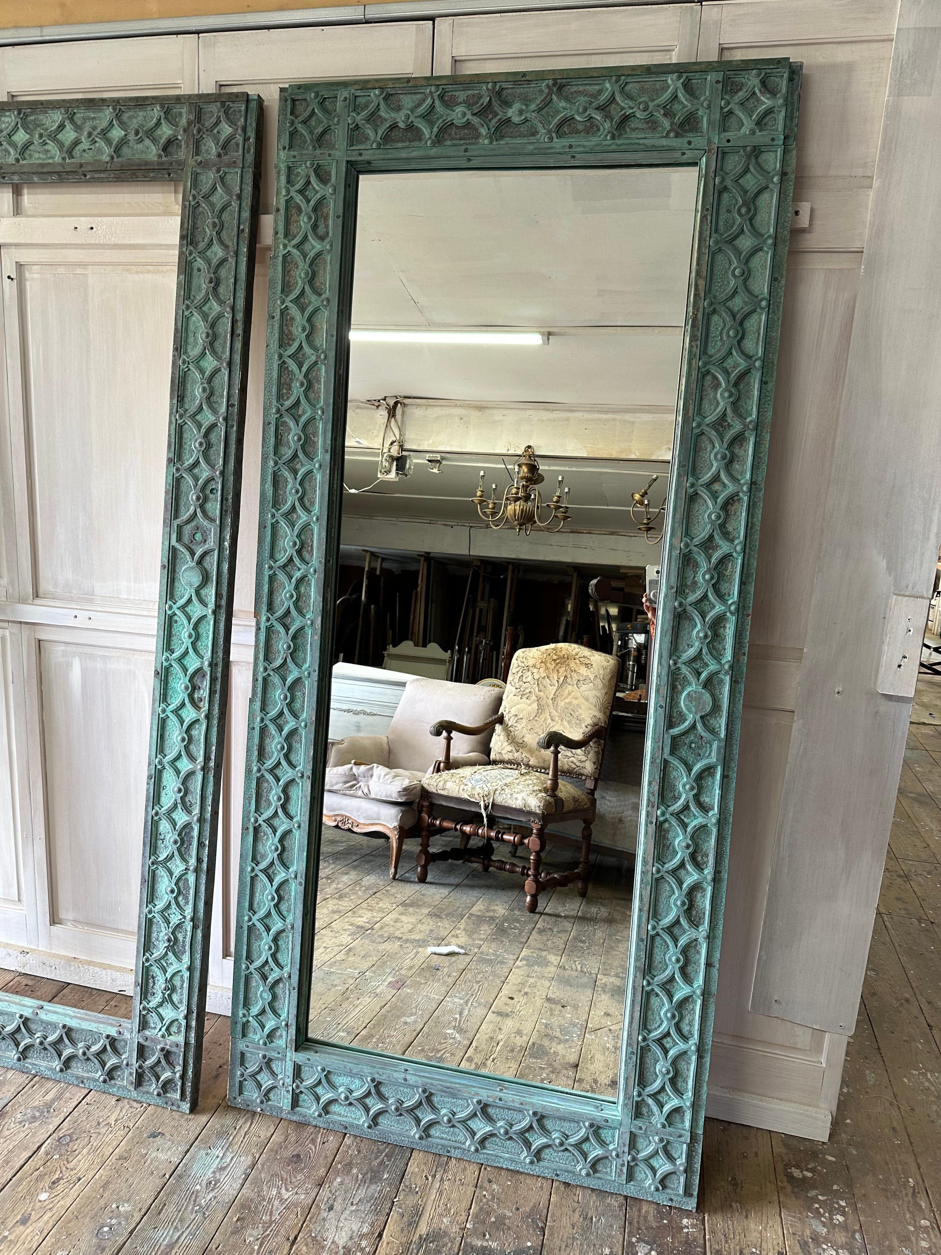A very special and rare antique French bronze floor,  wall mirror with beautiful green verdigris. The detailed geometric low relief fretwork decorated mirror was once an antique door that has been lovingly restored, reworked and made into mirror