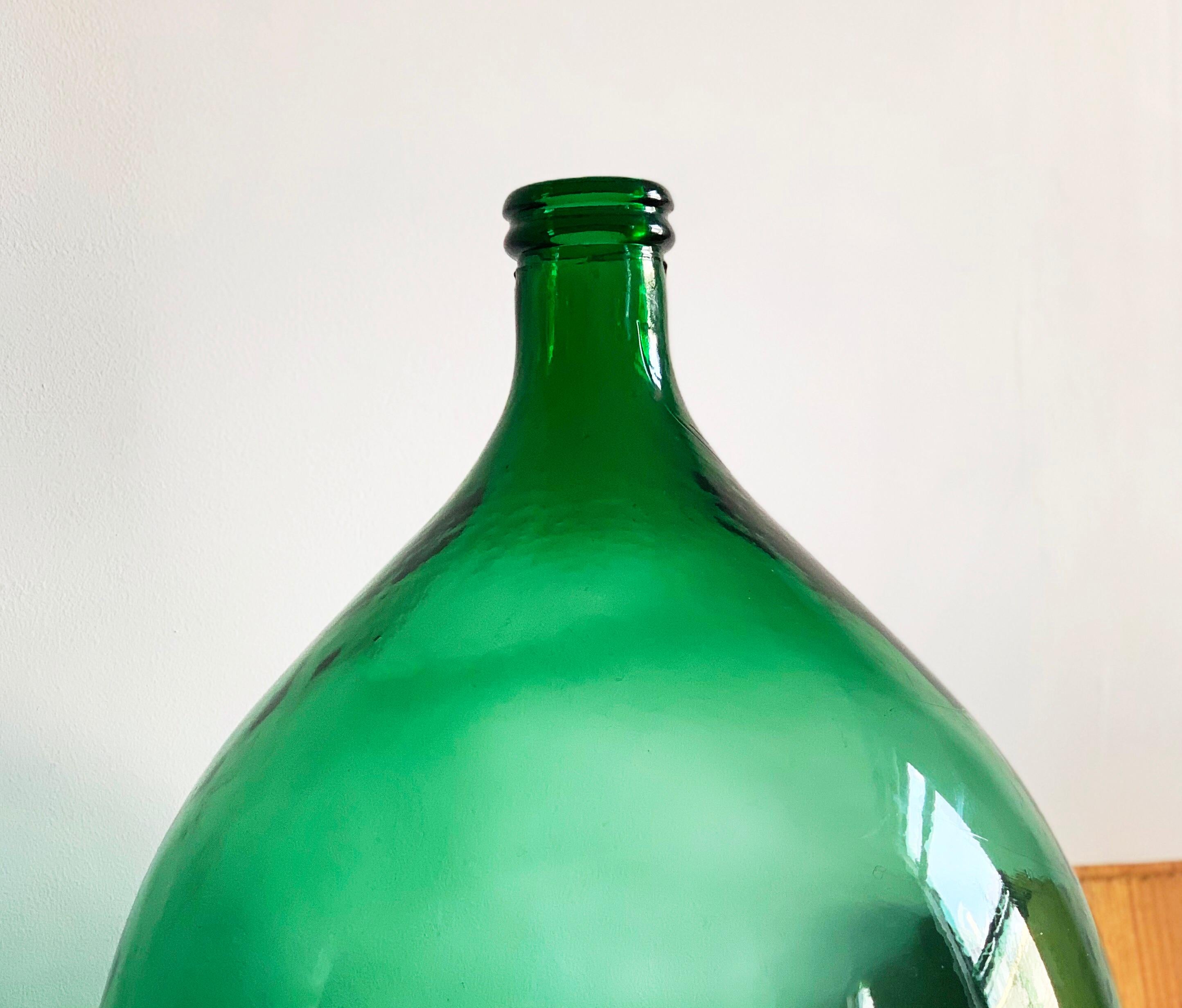 Beautiful and massive hand blown large demijohn green bottle. Early antique American blown green glass demijohn with a beautiful bold irregular sculptural form. Dates to anywhere from the late 18th-early part of the 19th century.
 
This is an Otto