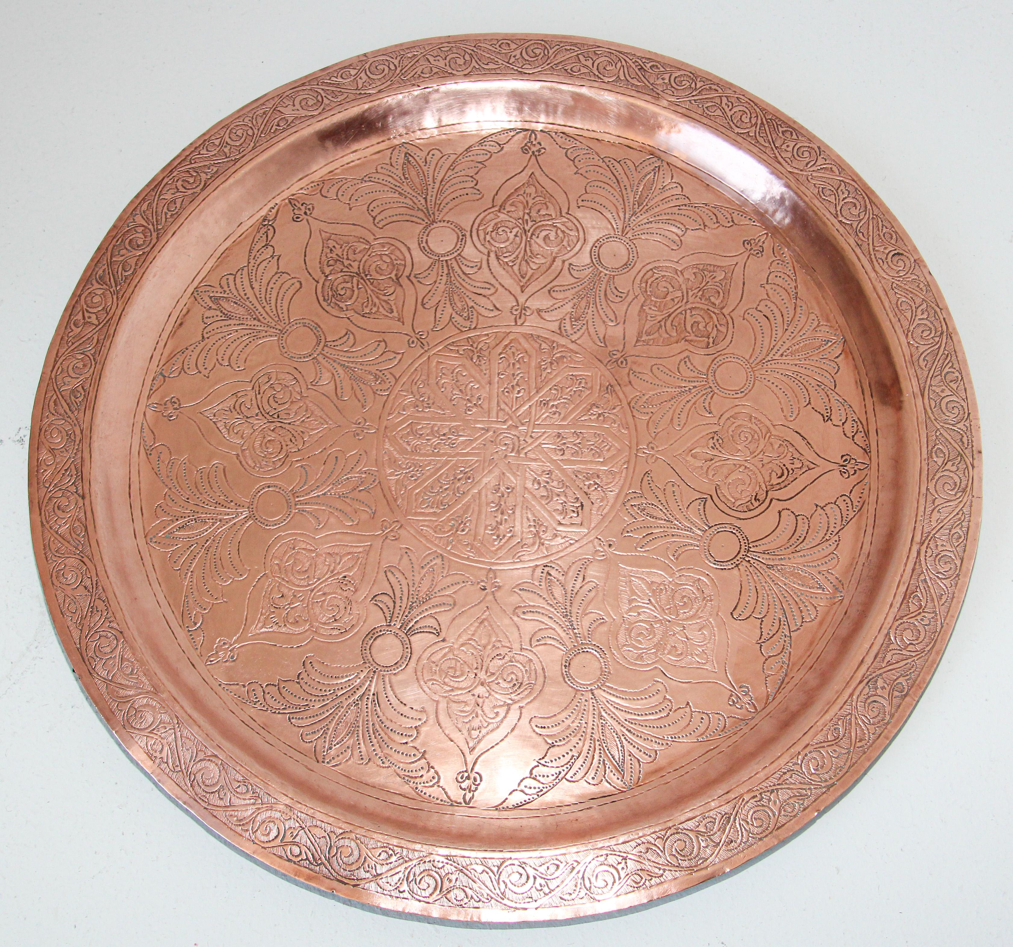 Moroccan Moorish style antique round copper tray.
The handcrafted circular copper metal platter is decorated and hammered with Islamic Moorish floral and geometric designs.
Heavy red metal copper plate with very fine hand chased floral and