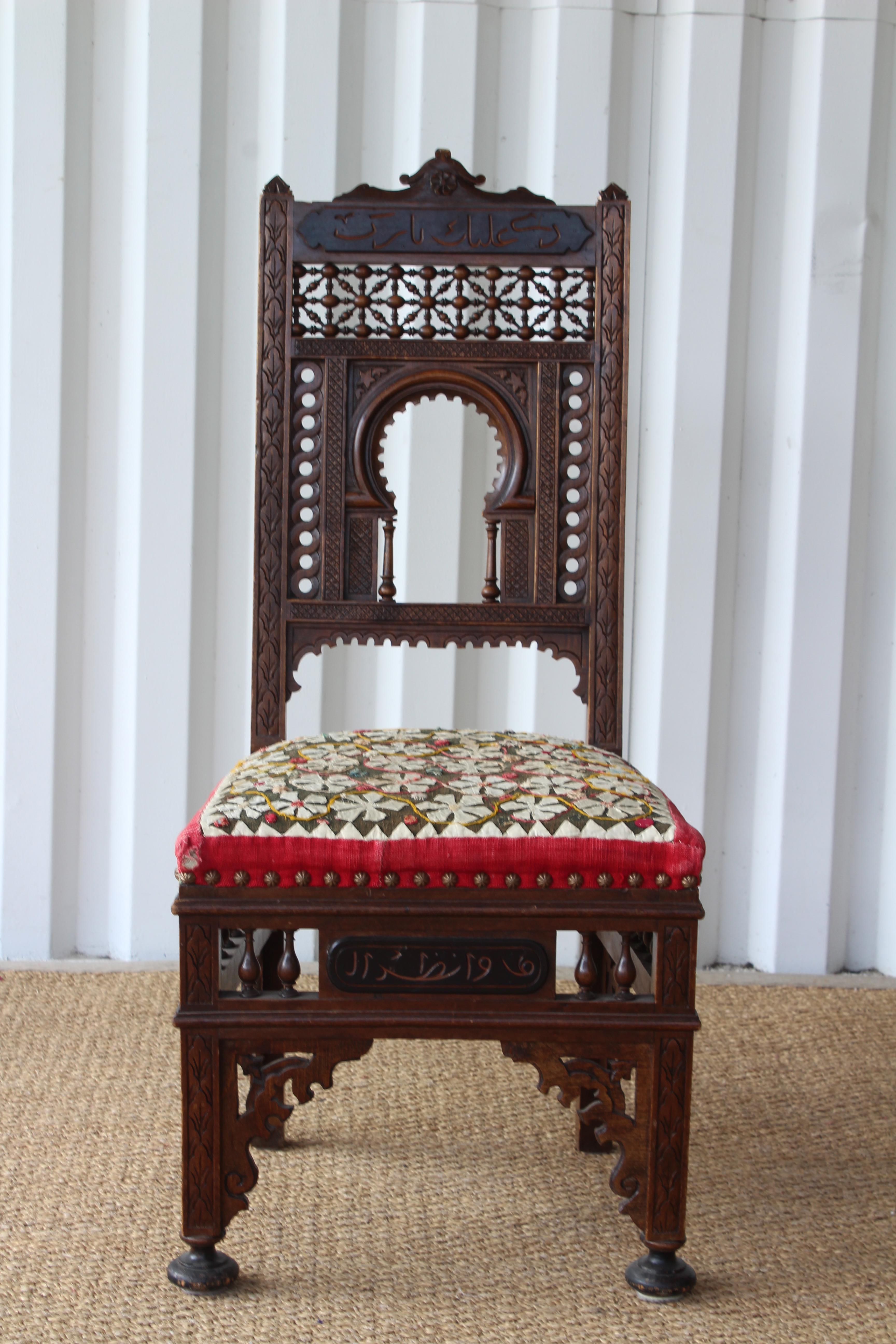 Antique Moorish side chair with intricate carved details. Vintage textile upholstered seat.