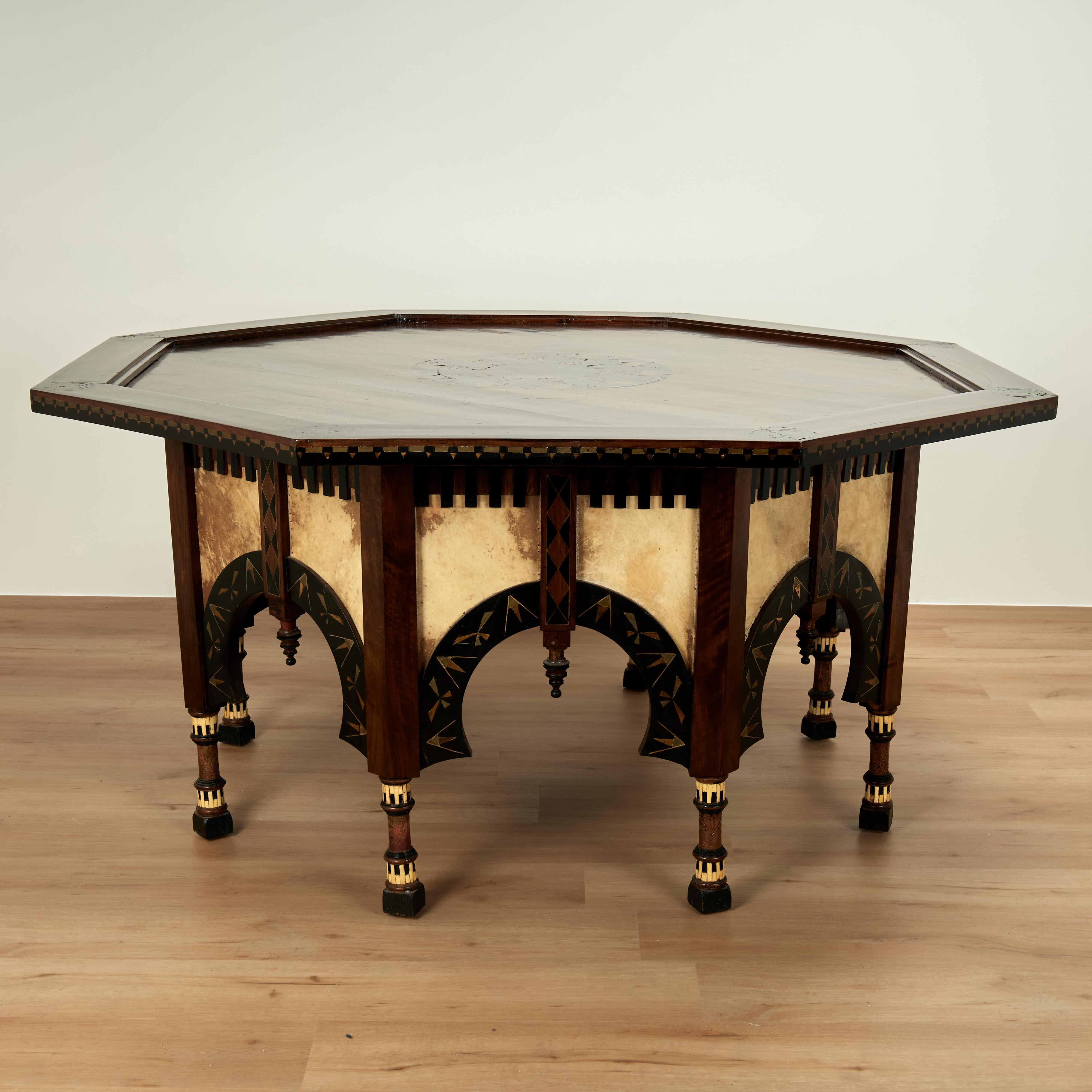 Impresionante mesa antigua hecha a mano en nogal a la manera de Bugatti, con tablero de forma octogonal con medallón central con incrustaciones geométricas sobre una base con arcos de estilo morisco decorada con exóticas incrustaciones de estilo art