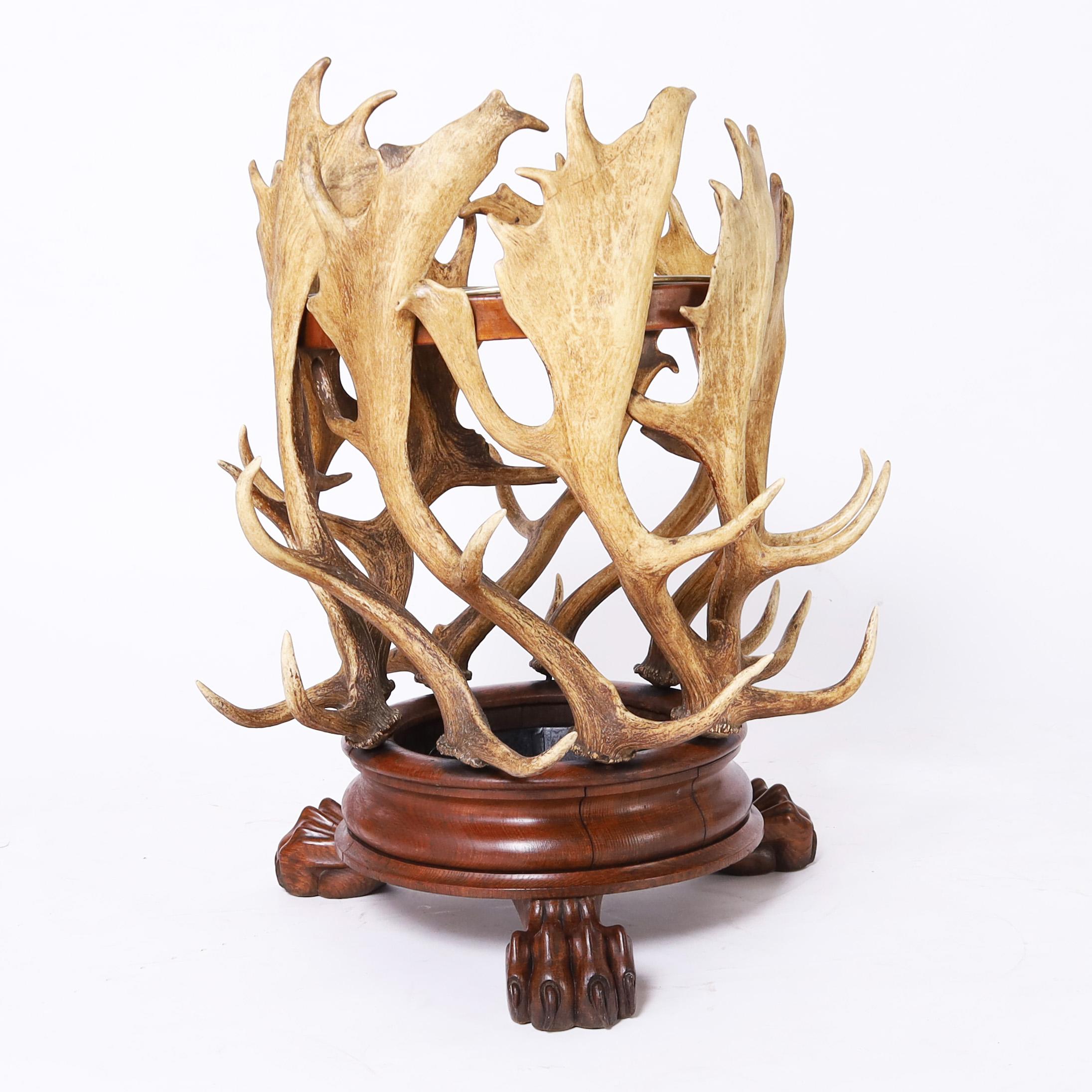 Rare and unusual antique umbrella or cane stand crafted with organic moose horns or antlers on a circular oak base with three carved oak paw feet.