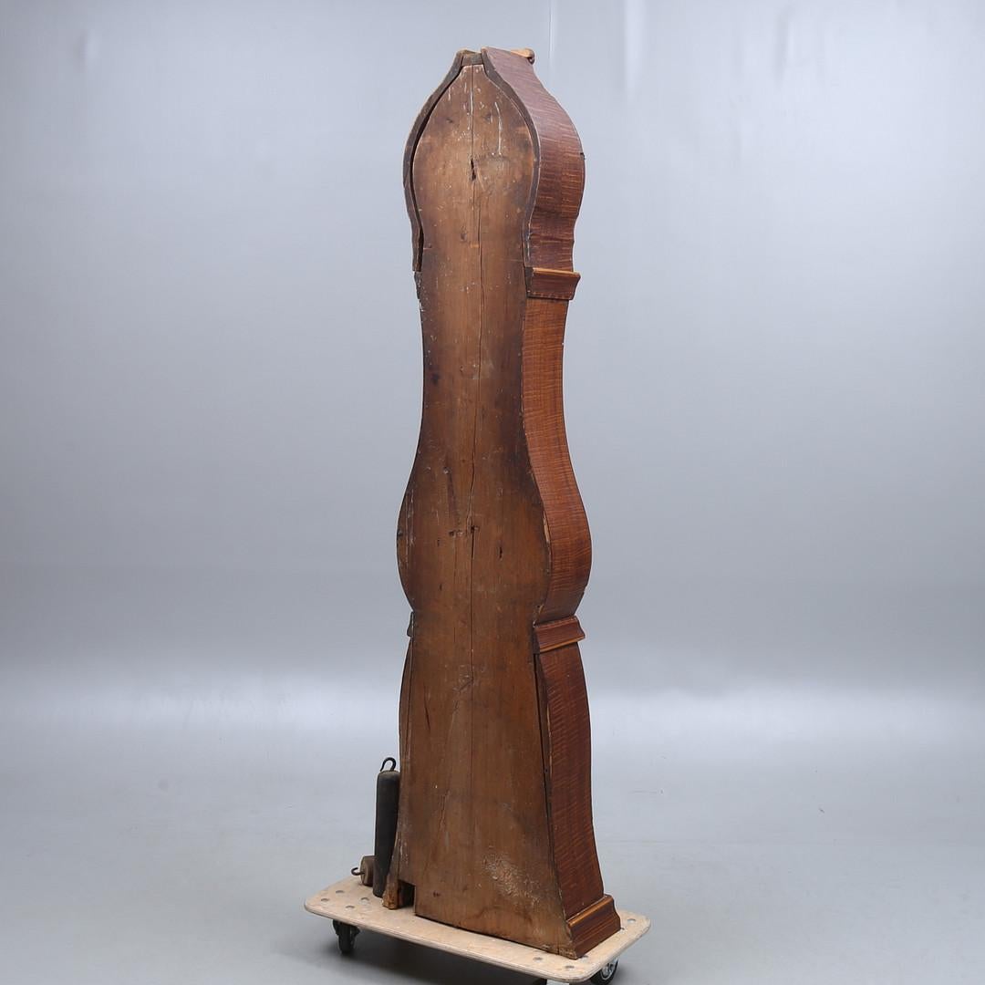 Antique Swedish mora clock from the early 1800s in Folk Art faux wood finish and simple detailing with a countryshape body and a roman numeral face in good condition. Measures: 205 cm.

It has the classic extended belly of a traditional Swedish mora