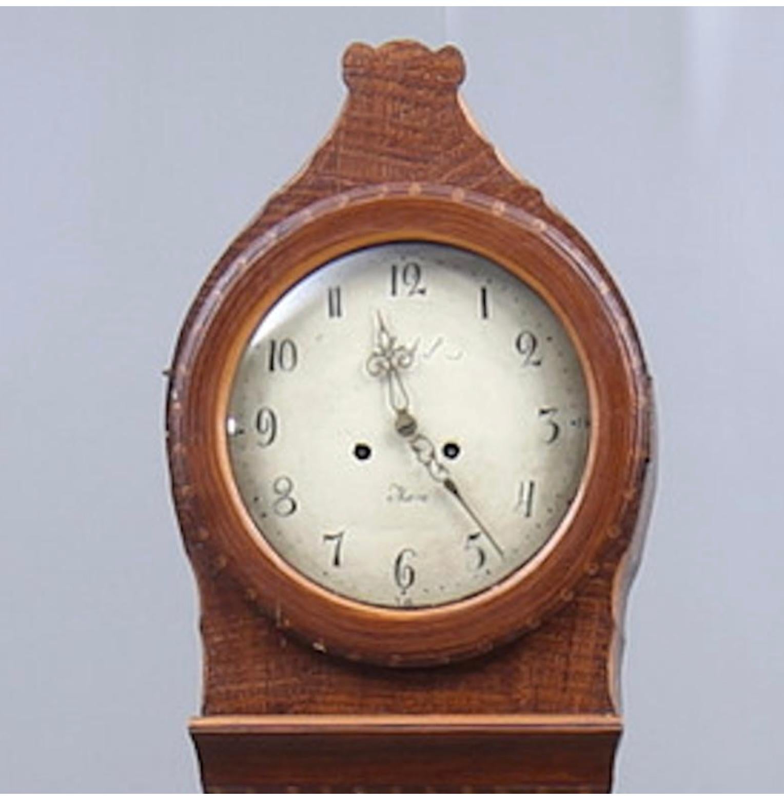 Antique Swedish mora clock from the early 1800s in Folk Art faux wood finish and simple detailing with a countryshape body and a roman numeral face in good condition. Measures: 205 cm.

It has the classic extended belly of a traditional Swedish mora