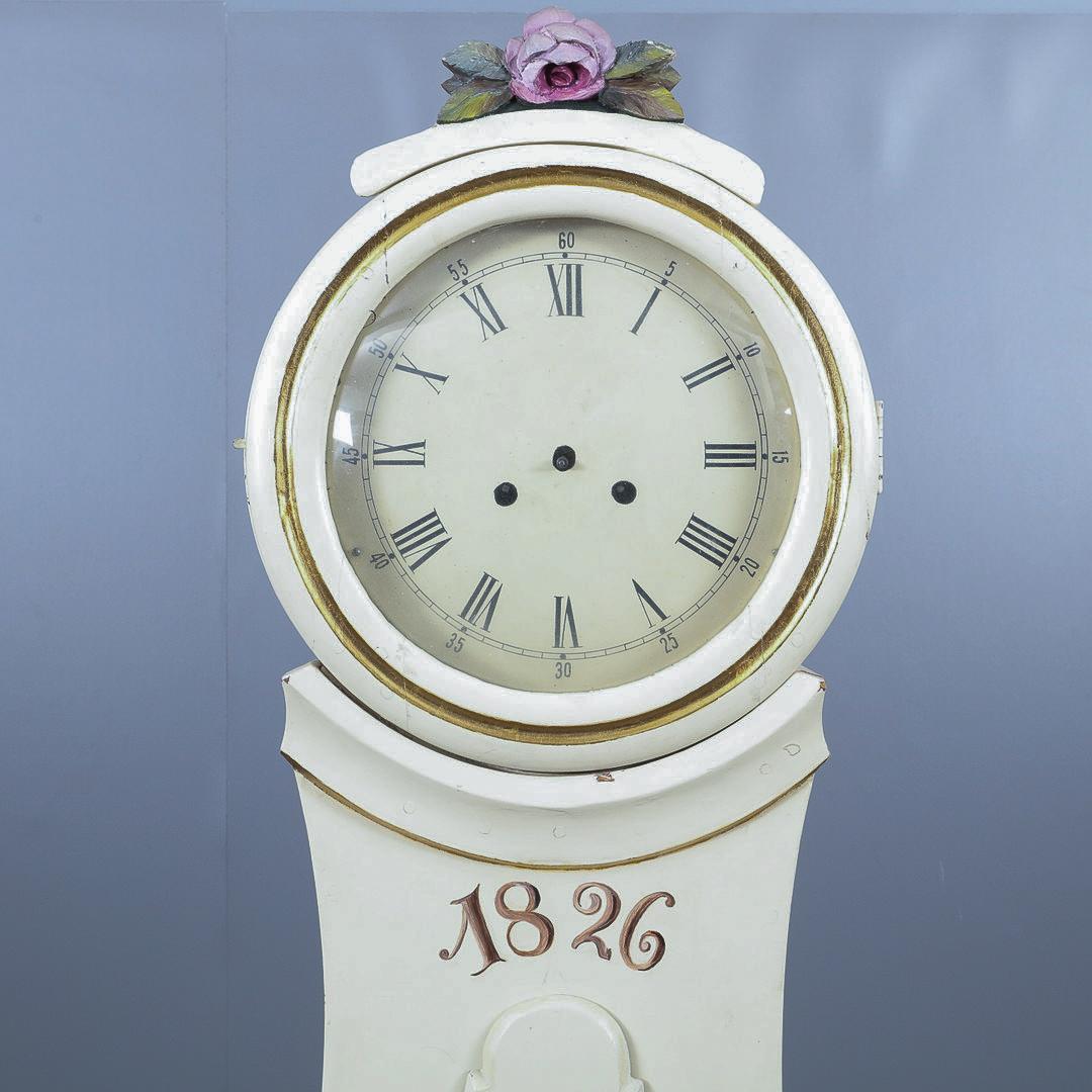 Antique Swedish mora clock from early 1800s in lovely white finish with polychromatic hand painted roses and flower detailing dated 1829 and carved roses detailing on the hood decoration and a wide belly body and a good roman numeral face.
