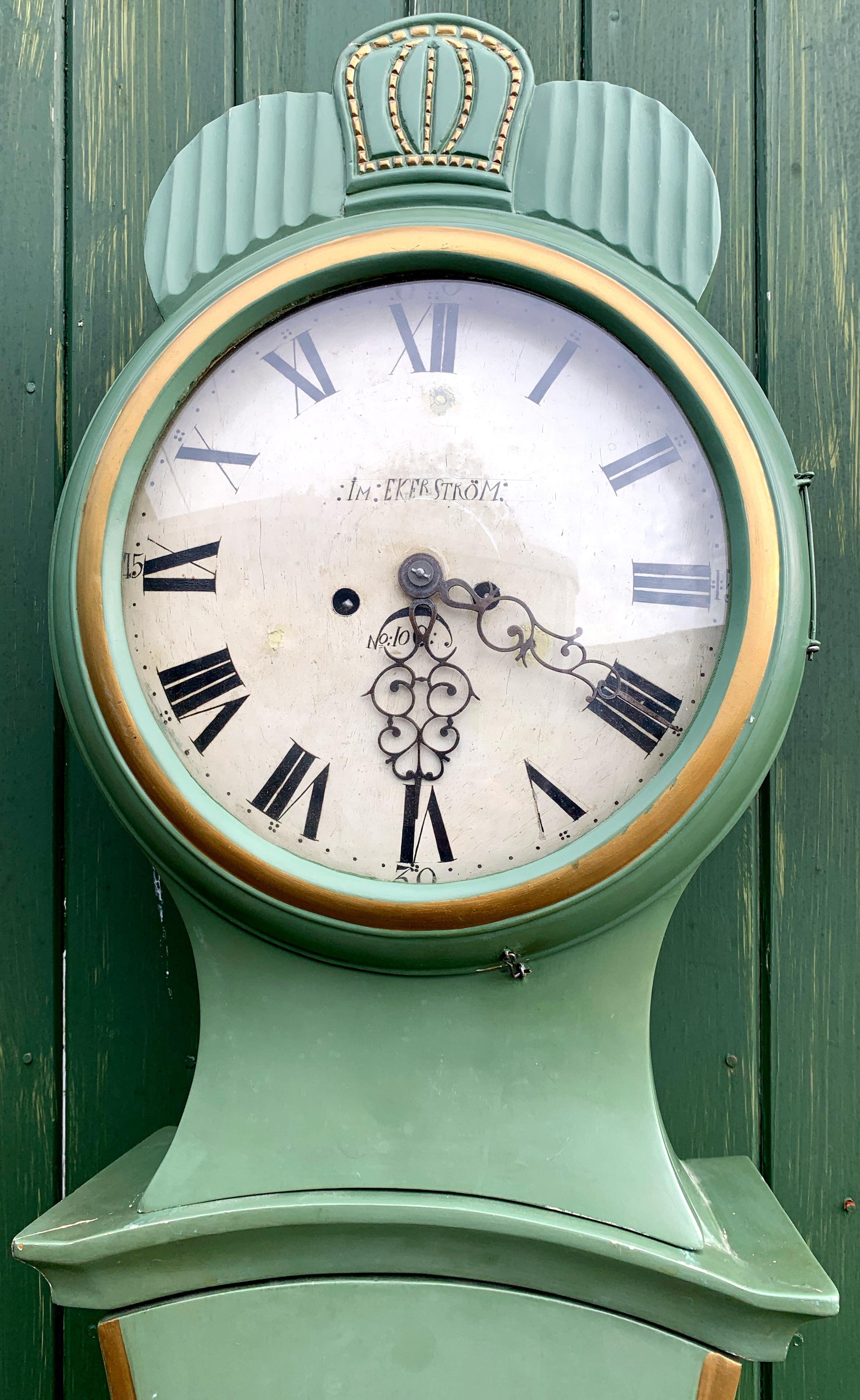 Antique Swedish mora clock from the early 1800s in lovely Green and Gold finish and Classic Fryksdall detailing with an extended belly shape body, Dual Star Motif and a clean face in good condition with makers name Ekerstrom. Measures: 200 cm.

It