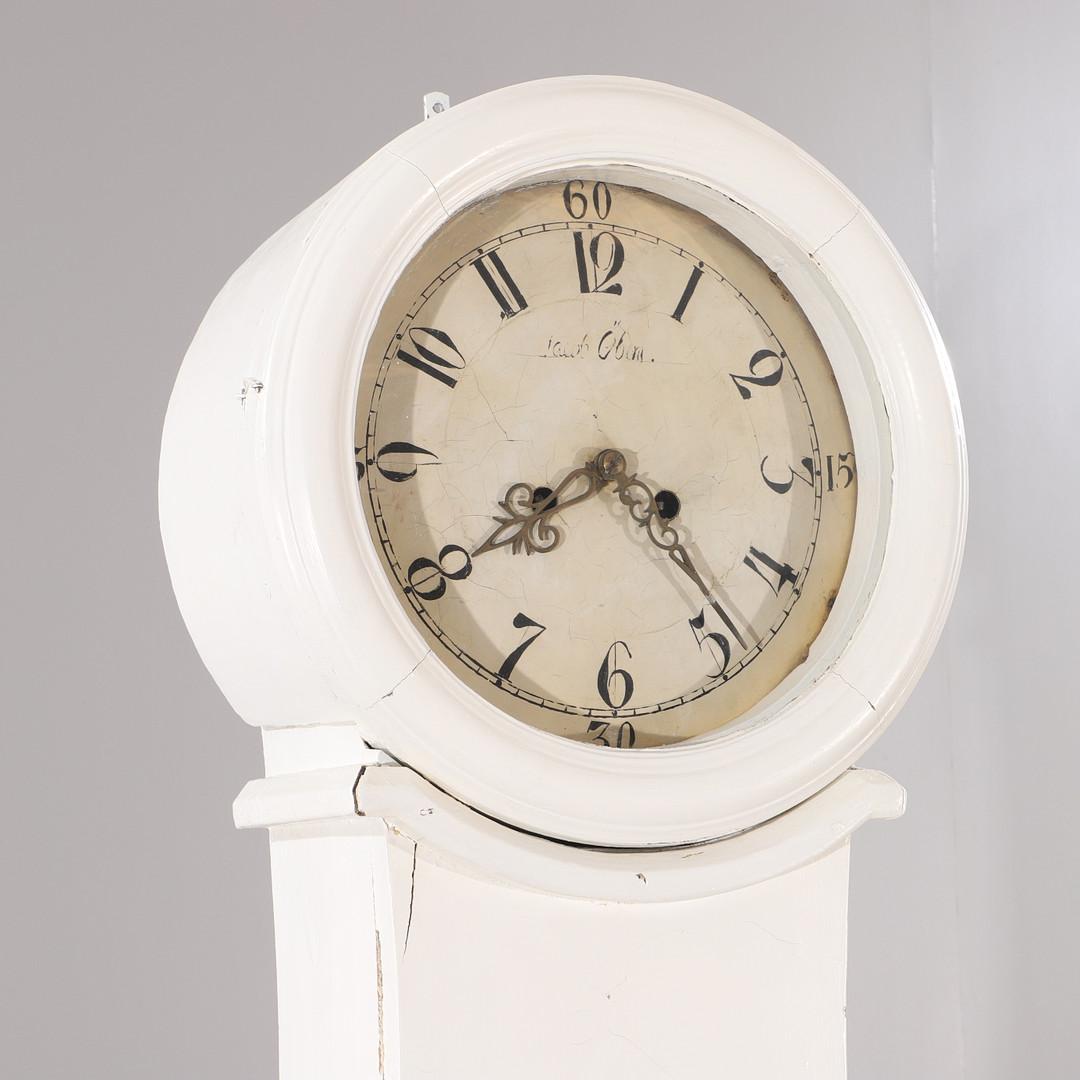 Antique Swedish mora clock from the early 1800s in a later white finish and slender shape body, simple crown and detail and a clean arabic numeral face with the makers name Jacob Oberg. Measures: 202 cm.

It has the Classic extended belly of a