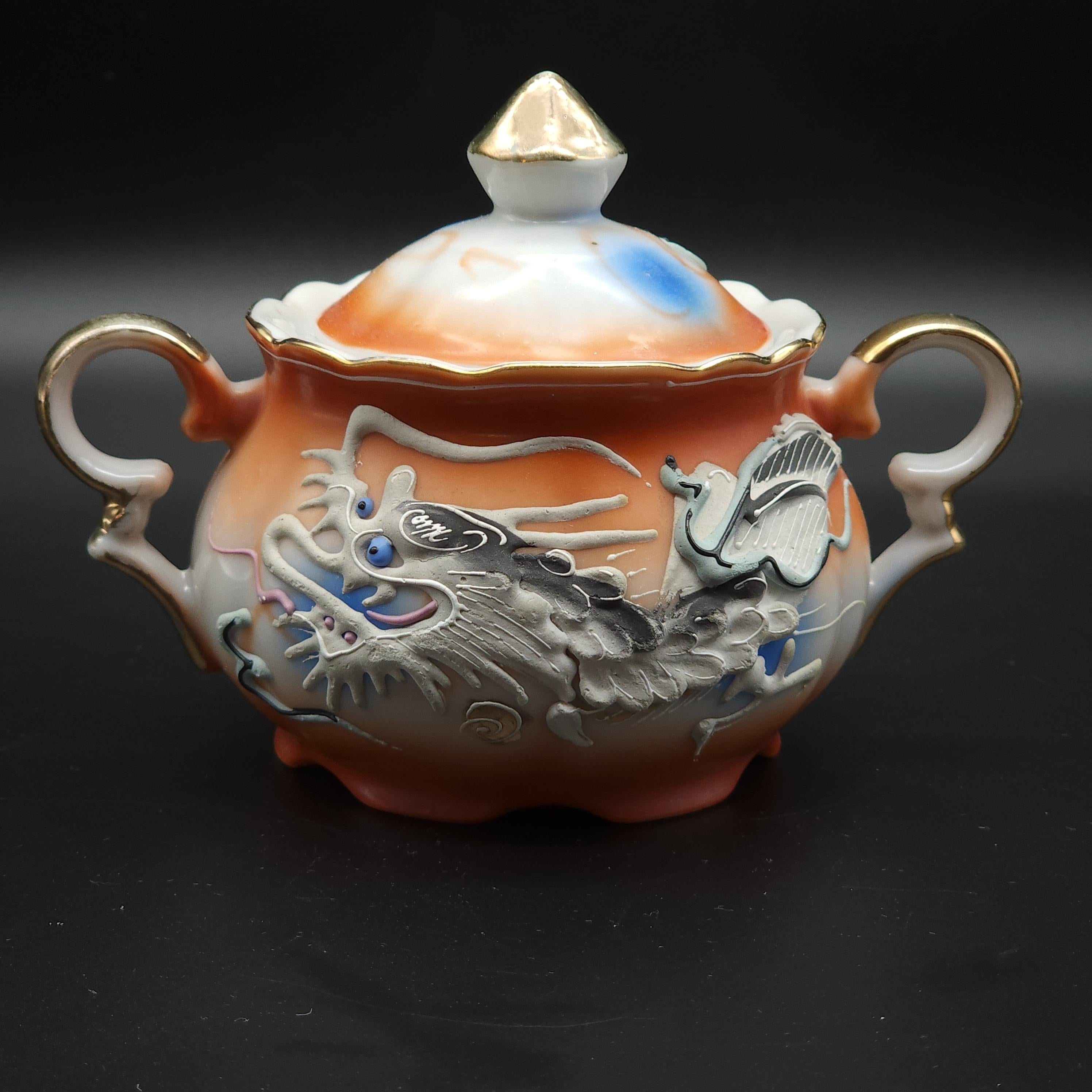 A beautiful artisanal handcrafted porcelain Dragon ware coffee set of 14 items. This set features a moriage dragon design. Eyes are decorated with deep blue glass beads. Hand painted in a rich red-orange color and gilded with 22K gold.

Cup Height: