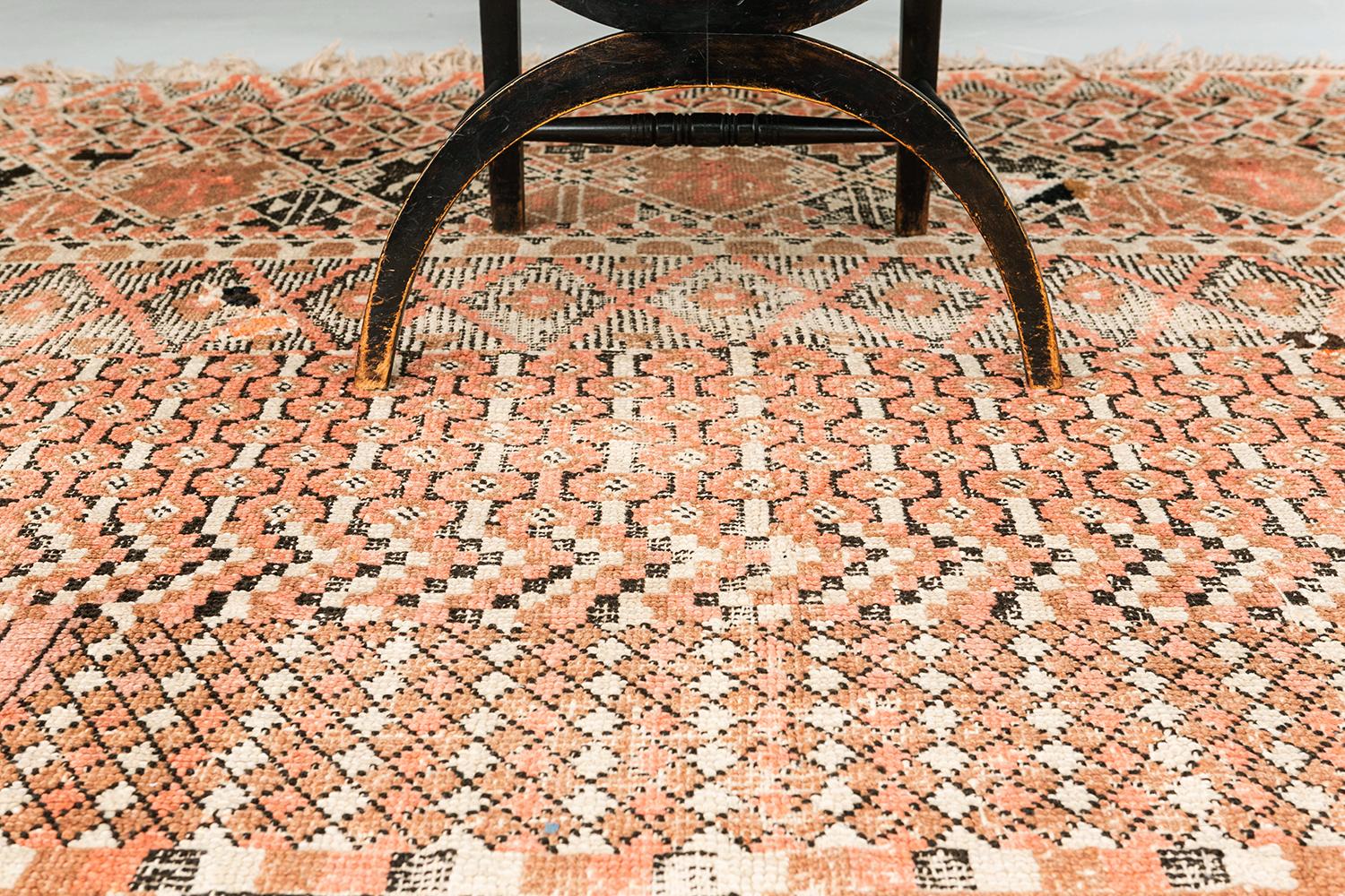 An antique Moroccan Beni M'Guild in beautiful coral, brown, and ivory. This wool pile weave is from the northern Middle Atlas Mountains of Morocco. The Beni M'Guild tribe is also known for their tone-on-tone designs with geometric patterning. This