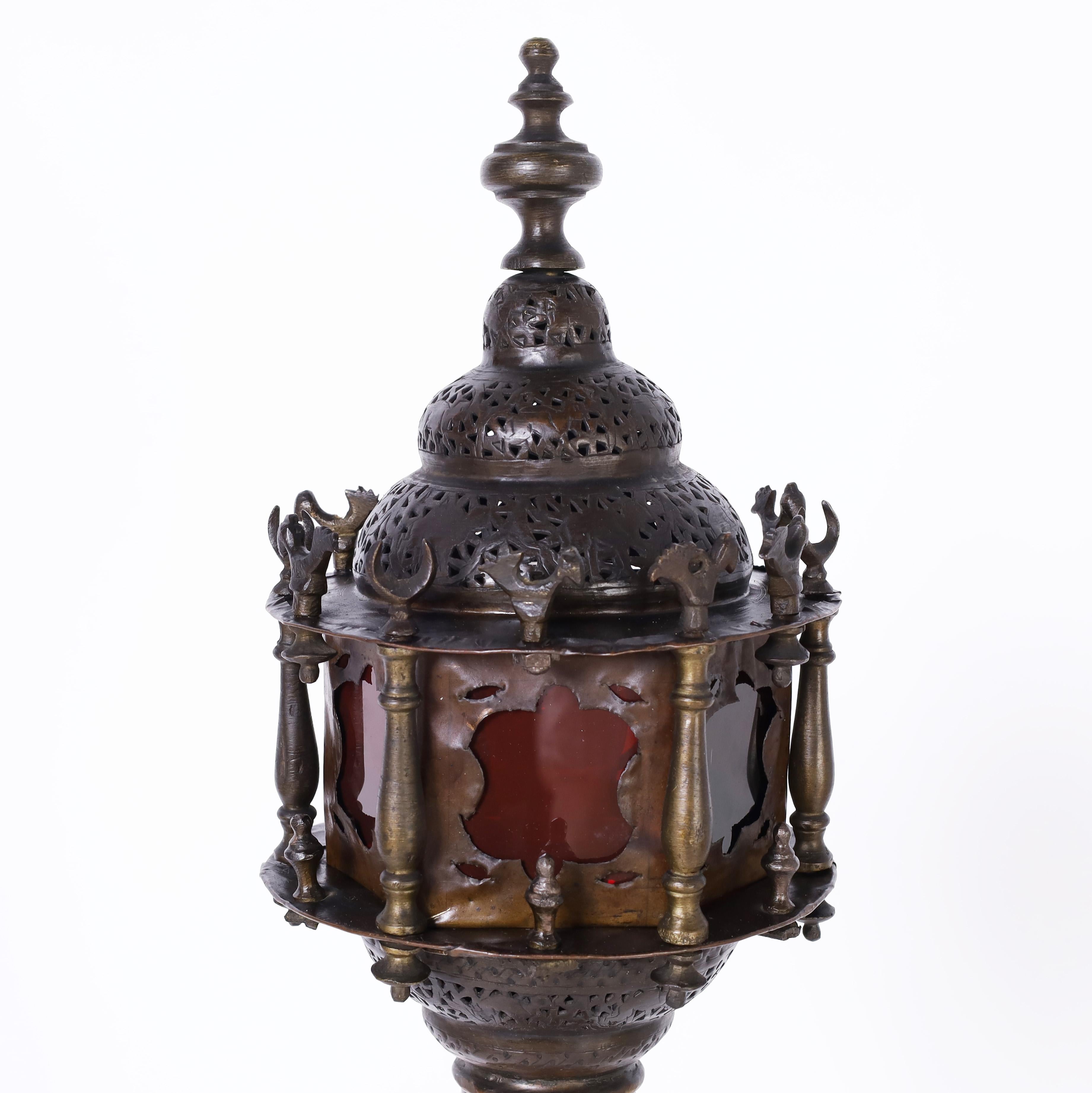 Seltene und exotische antike marokkanische Stehlampe, handgefertigt aus perforiertem Messing mit bronzeartiger Patina und architektonischer Form mit zwei Lichtstationen, beide mit rotem und blauem Buntglas. 