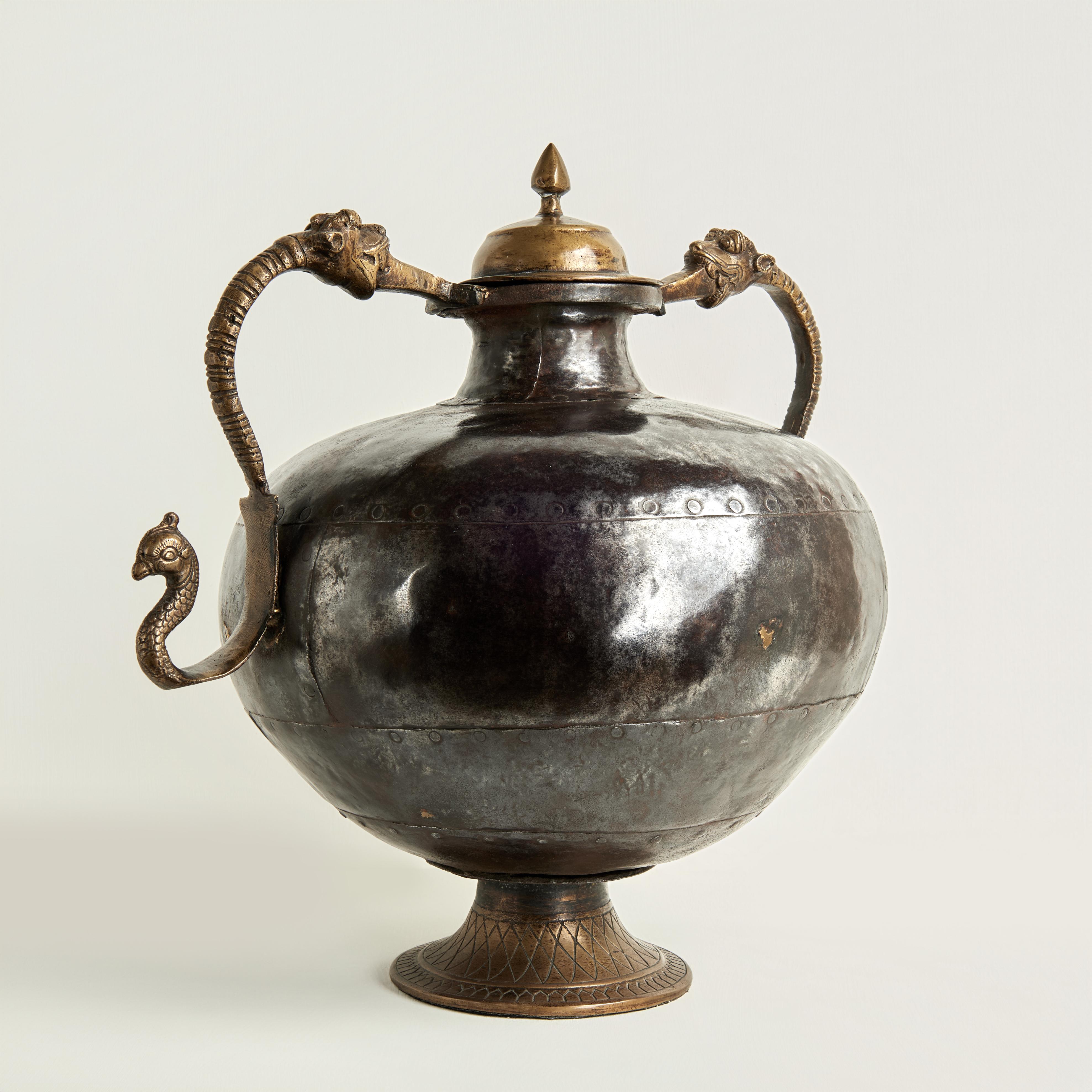 Incantevole vaso con coperchio marocchino antico, realizzato a mano con un corpo martellato e rivettato e caratterizzato da un coperchio in bronzo fuso, una base e un serpente mitologico con teste di gatto come manici.