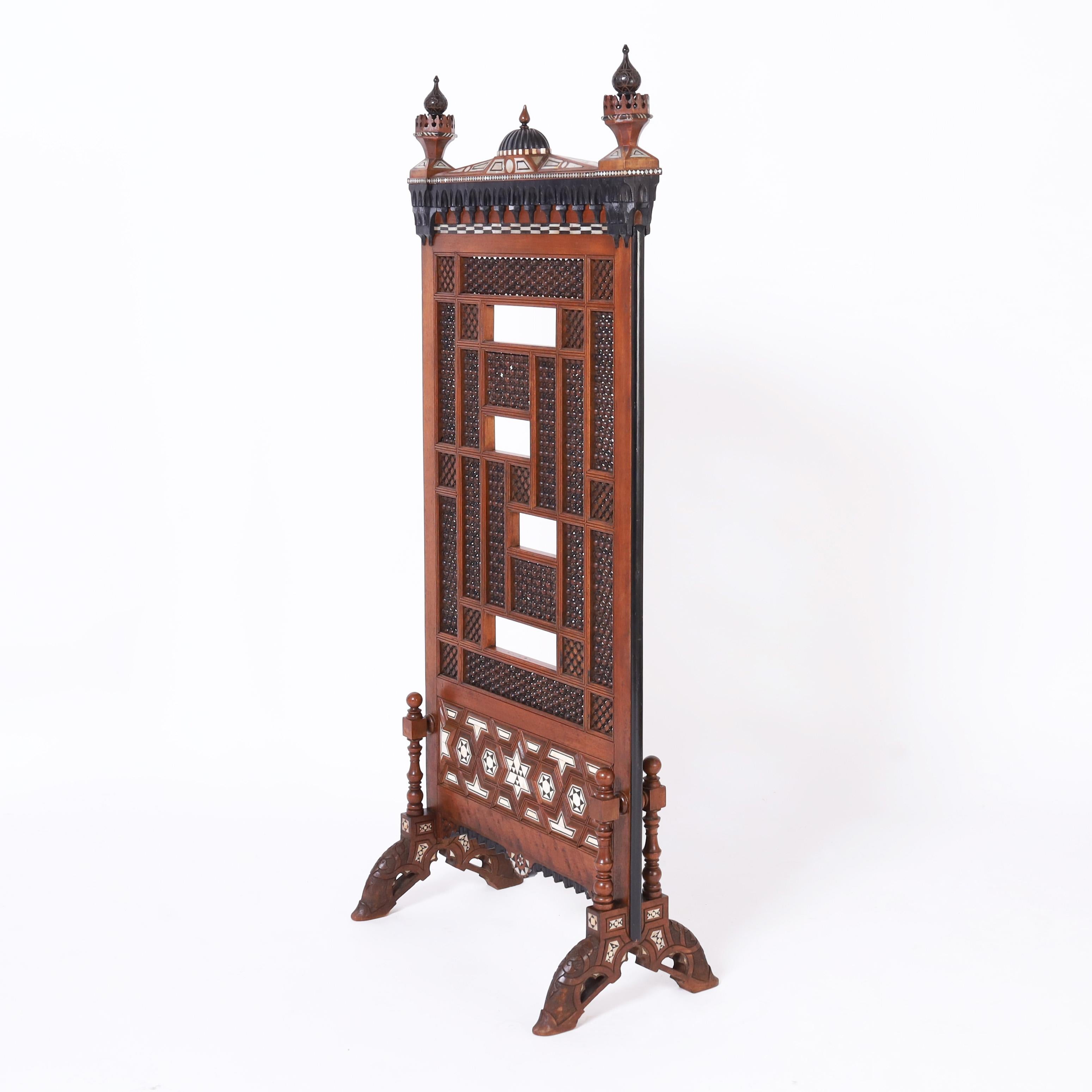Antique Moroccan screen crafted with mahogany in an architecturally interesting form featuring onion dome finials, geometric inlays of mother of pearl, bone and ebony, with carved and ebonized reliefs, stick and ball panels, turned supports and