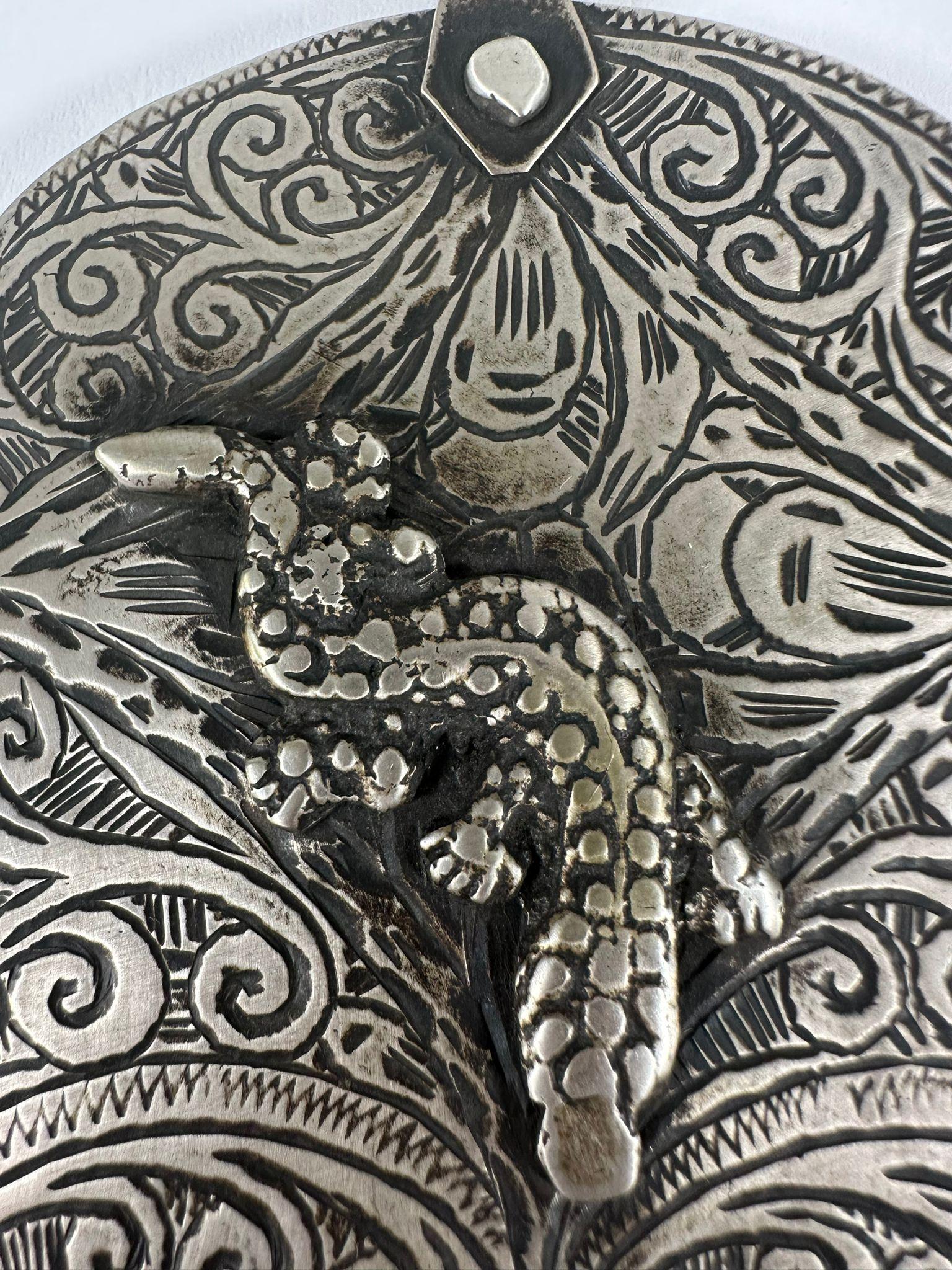This rare handmade Moroccan Hamsa pendant, crafted in 1880, is made of intricately engraved silver and features a three-dimensional lizard, a symbol of health, healing, and regeneration in North African Jewish tradition. The Hamsa, a well-known