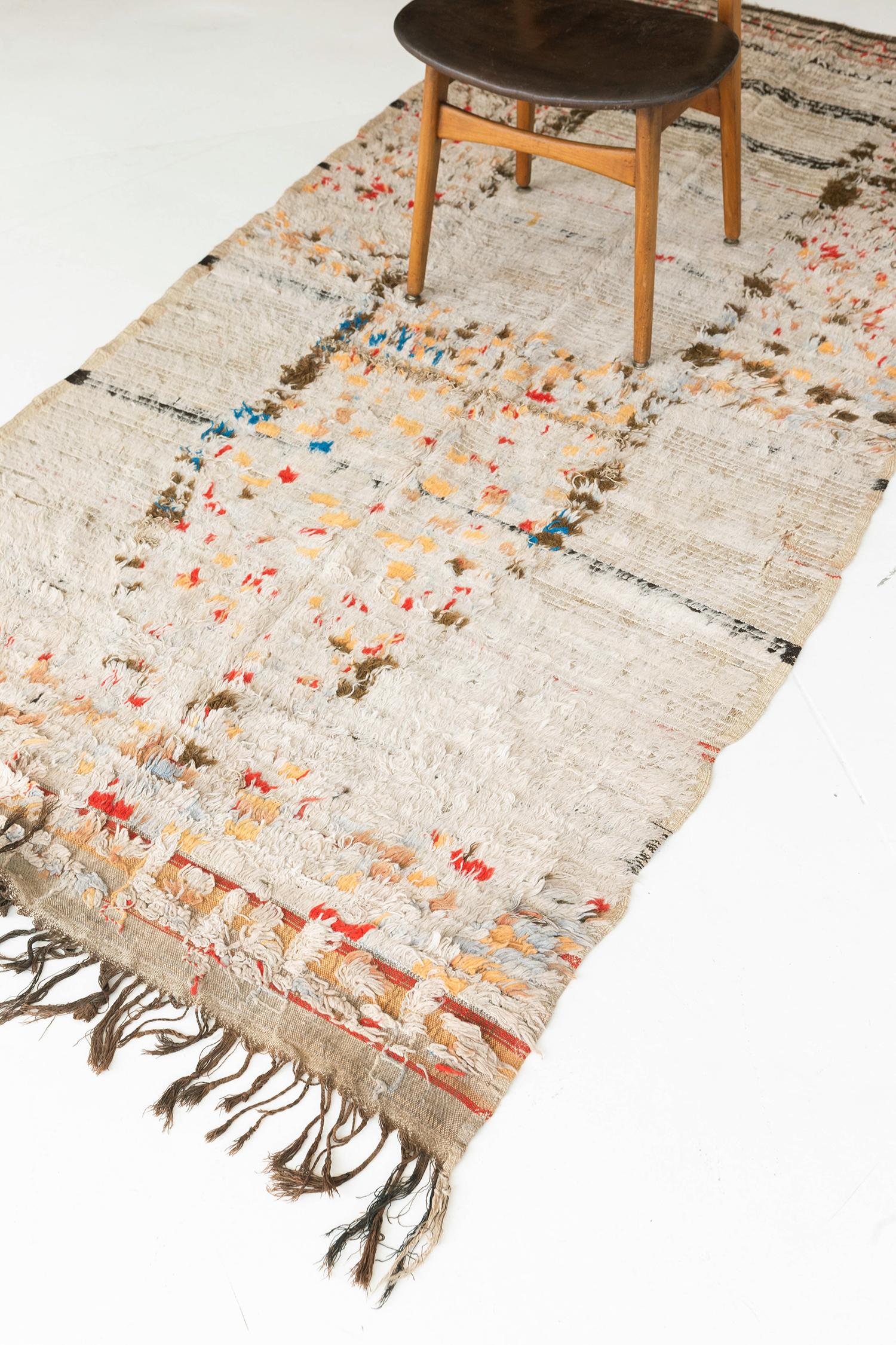 Blending its primitive charm and ancient symbolism, this Antique Moroccan High Atlas Tribe rug features an abstract pattern of the Berber culture. Through the ambiguous vibrant elements that come together into a network in a hygge and elegant