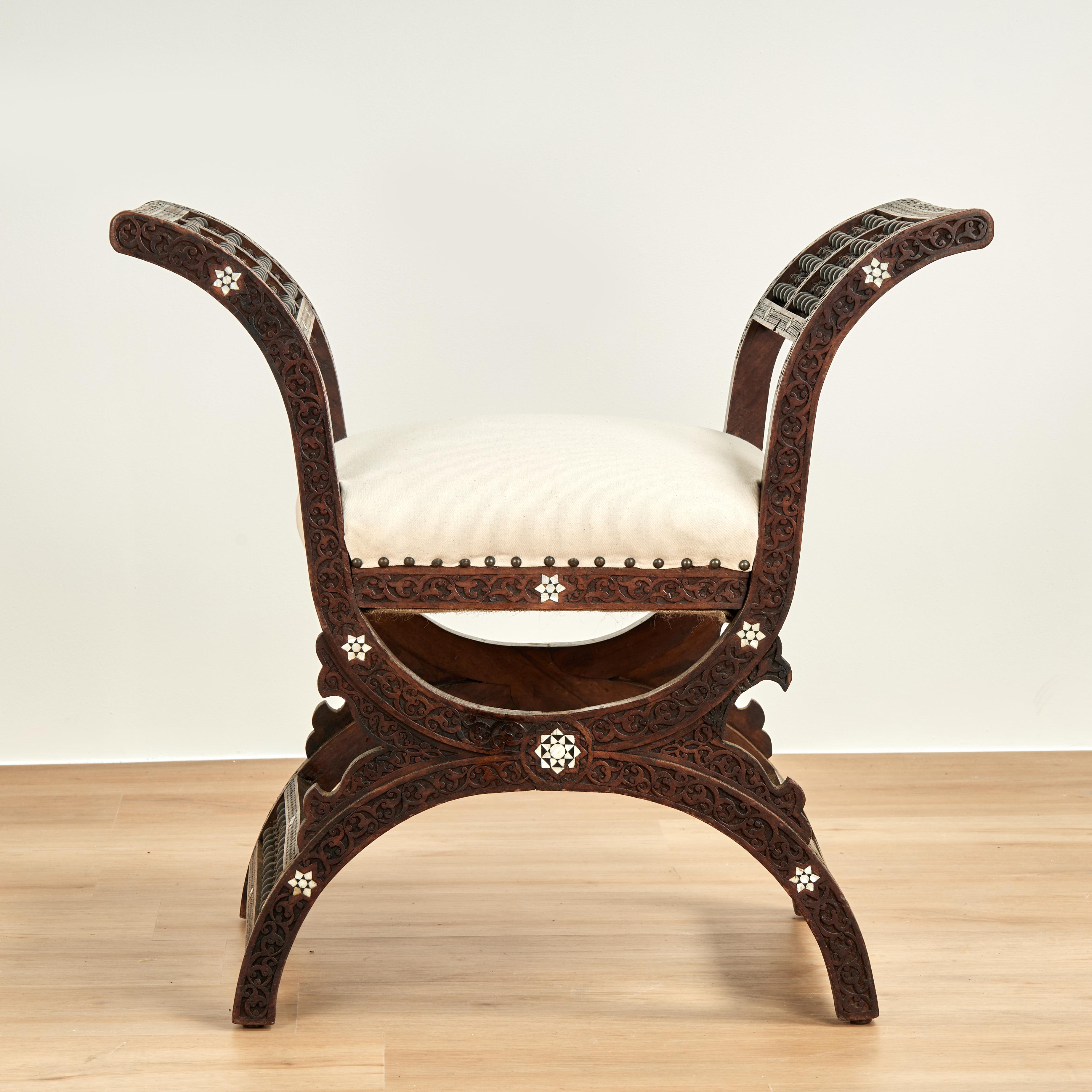 Enchanting antique Moroccan bench crafted in walnut in a classic moorish form featuring floral carvings, stick and ball panels and inlaid mother of pearl.