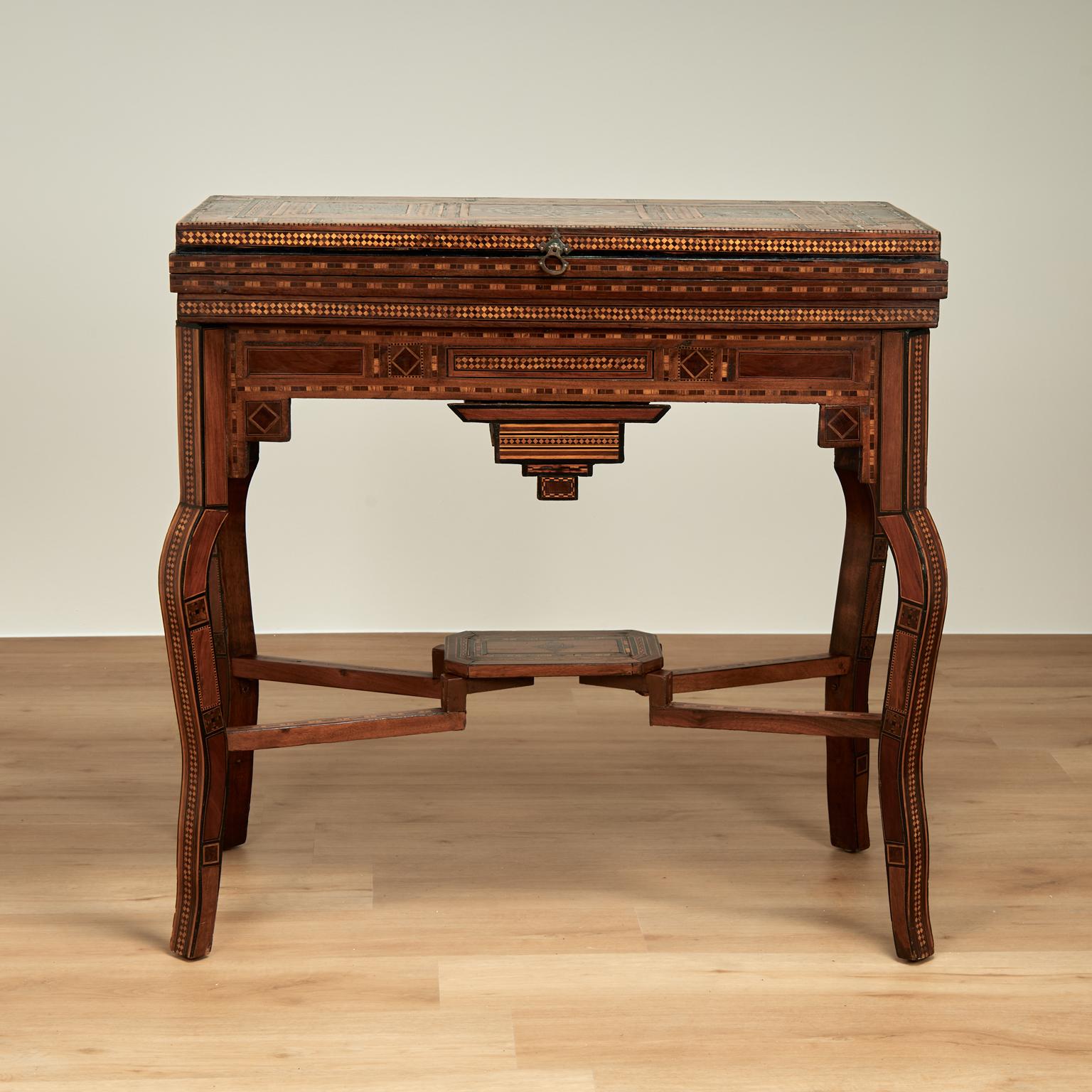 Impressionnante table de jeu marocaine ancienne en noyer avec des incrustations et des marqueteries élaborées en acajou, noyer, ébène, bois de roi et nacre. Le dessus de la console s'ouvre sur une table à cartes recouverte de feutre qui s'ouvre sur