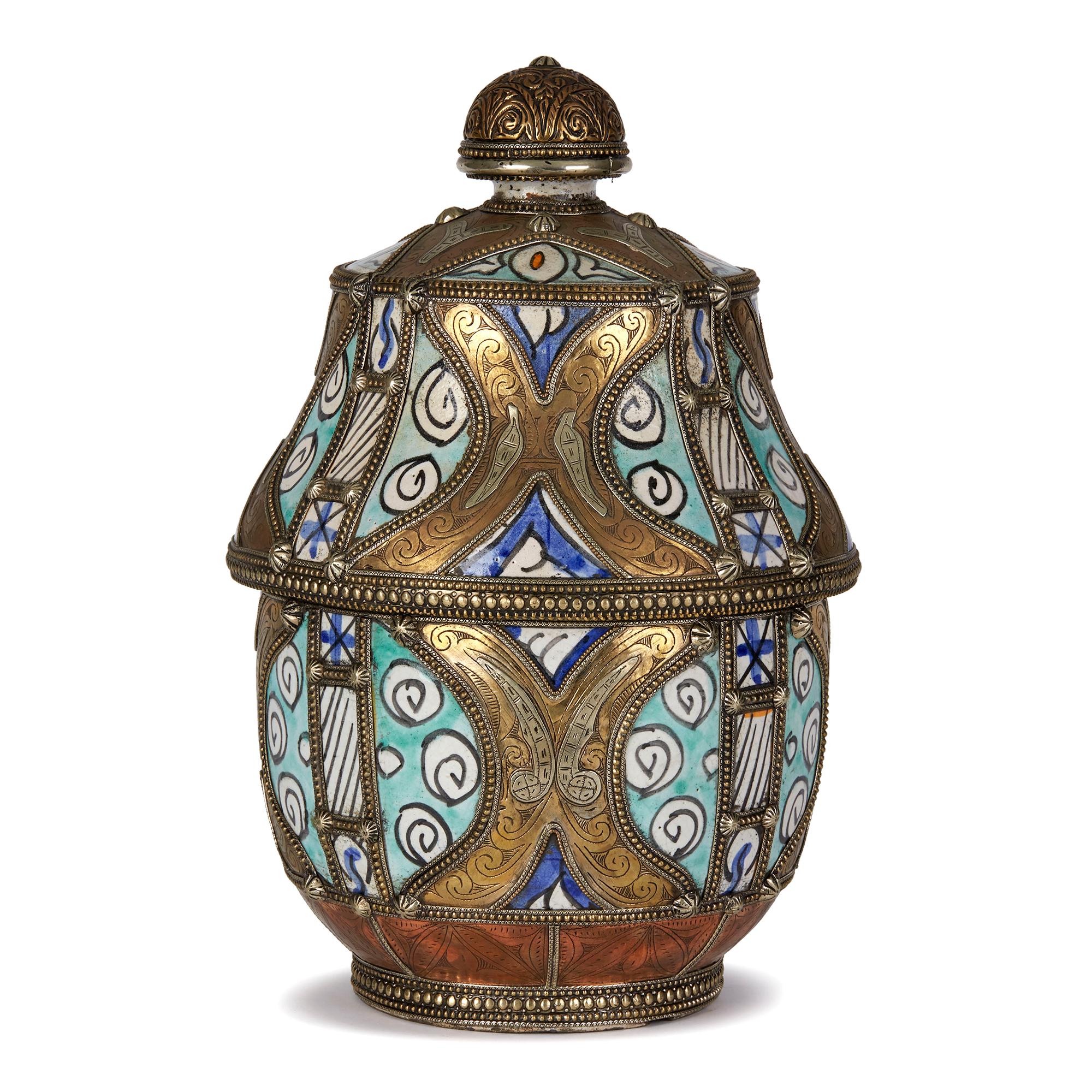 Antique Moroccan 'Jobbana' ceramic lidded butter pot glazed with blue, turquoise and orange with black patterned outlines on a white ground decoration with ornate etched white metal, copper and brass mounts with beaded rims around the edges, the